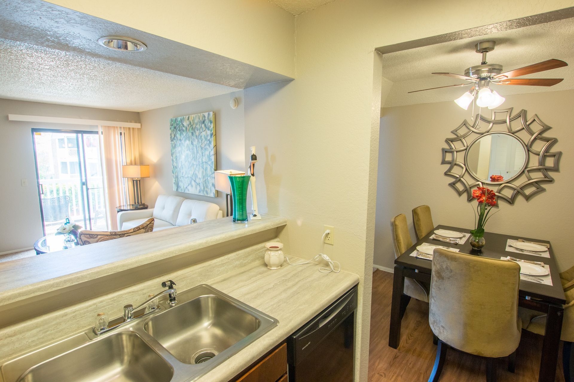 A kitchen with a sink , dishwasher , dining table and chairs.