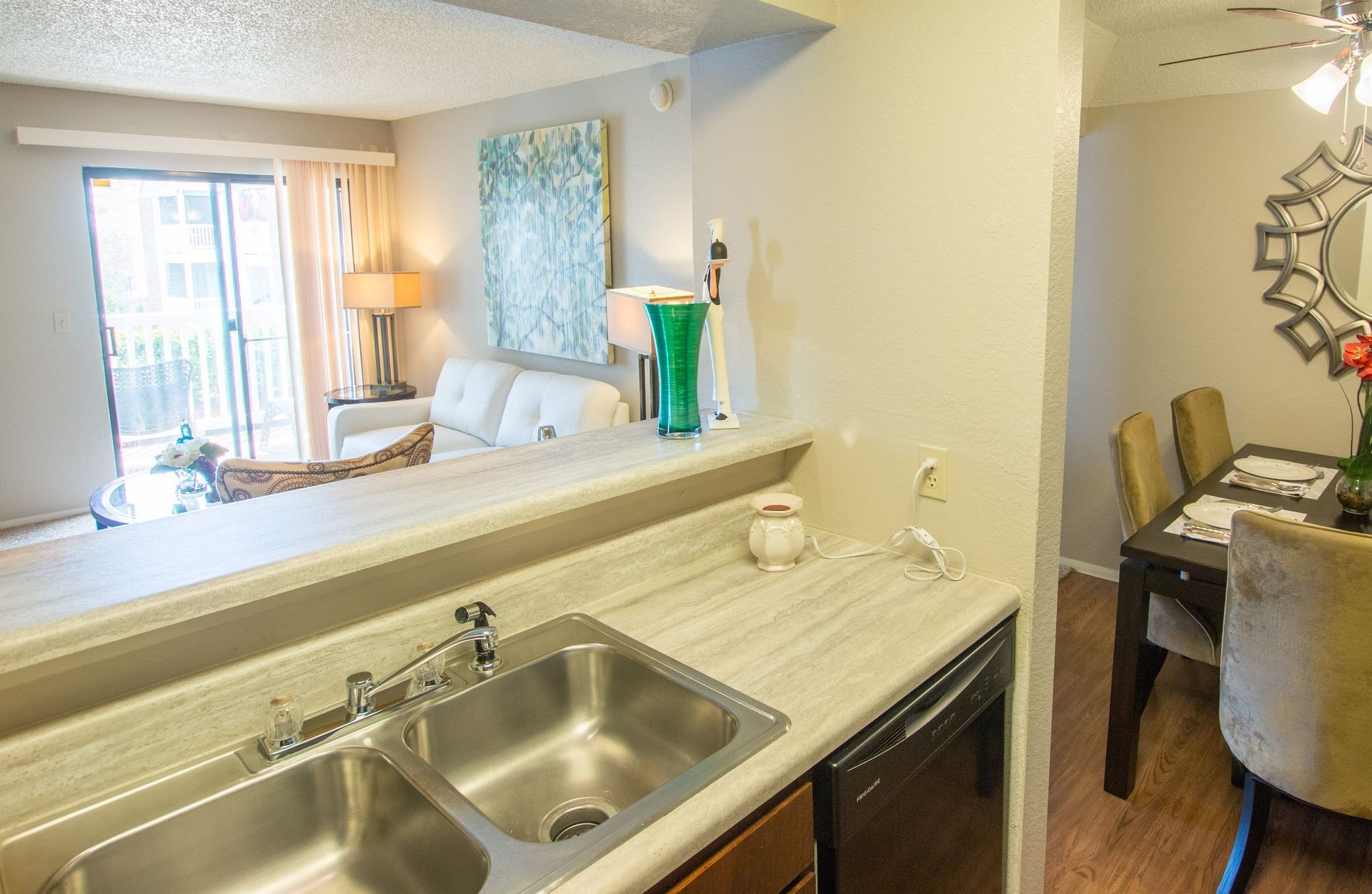 A kitchen with a sink , dishwasher , dining table and chairs.