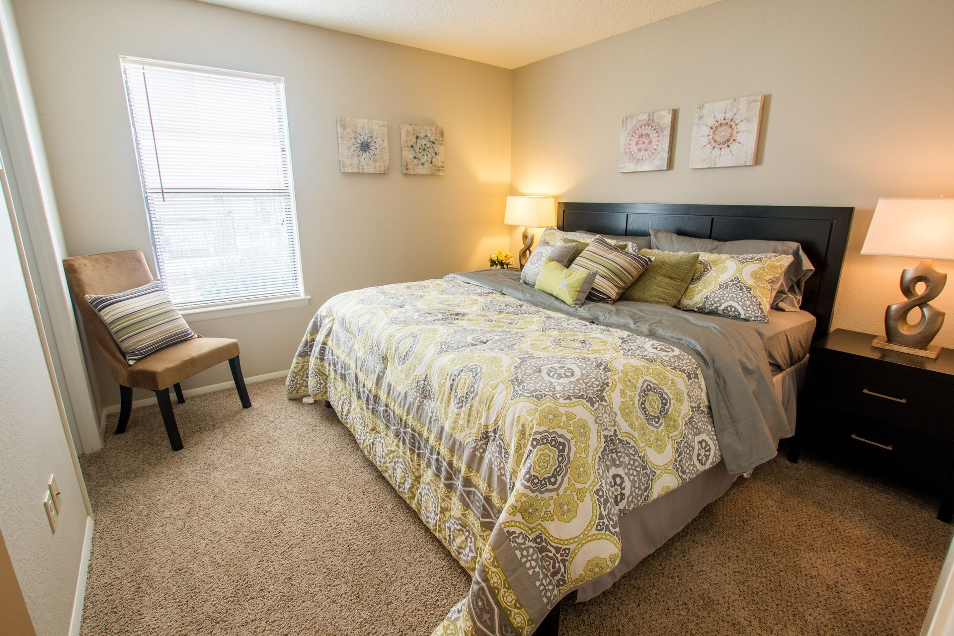 A bedroom with a king size bed , nightstand , chair and window.