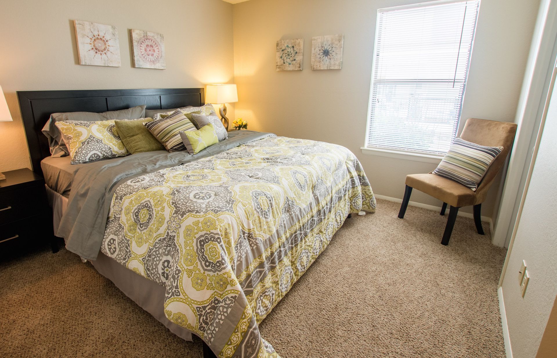 A bedroom with a bed , chair , nightstand and window.