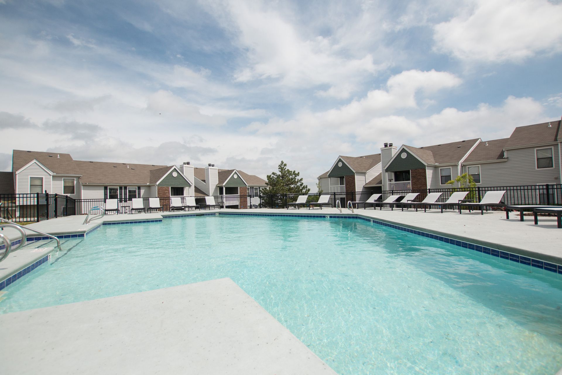 A large swimming pool in front of a row of houses.