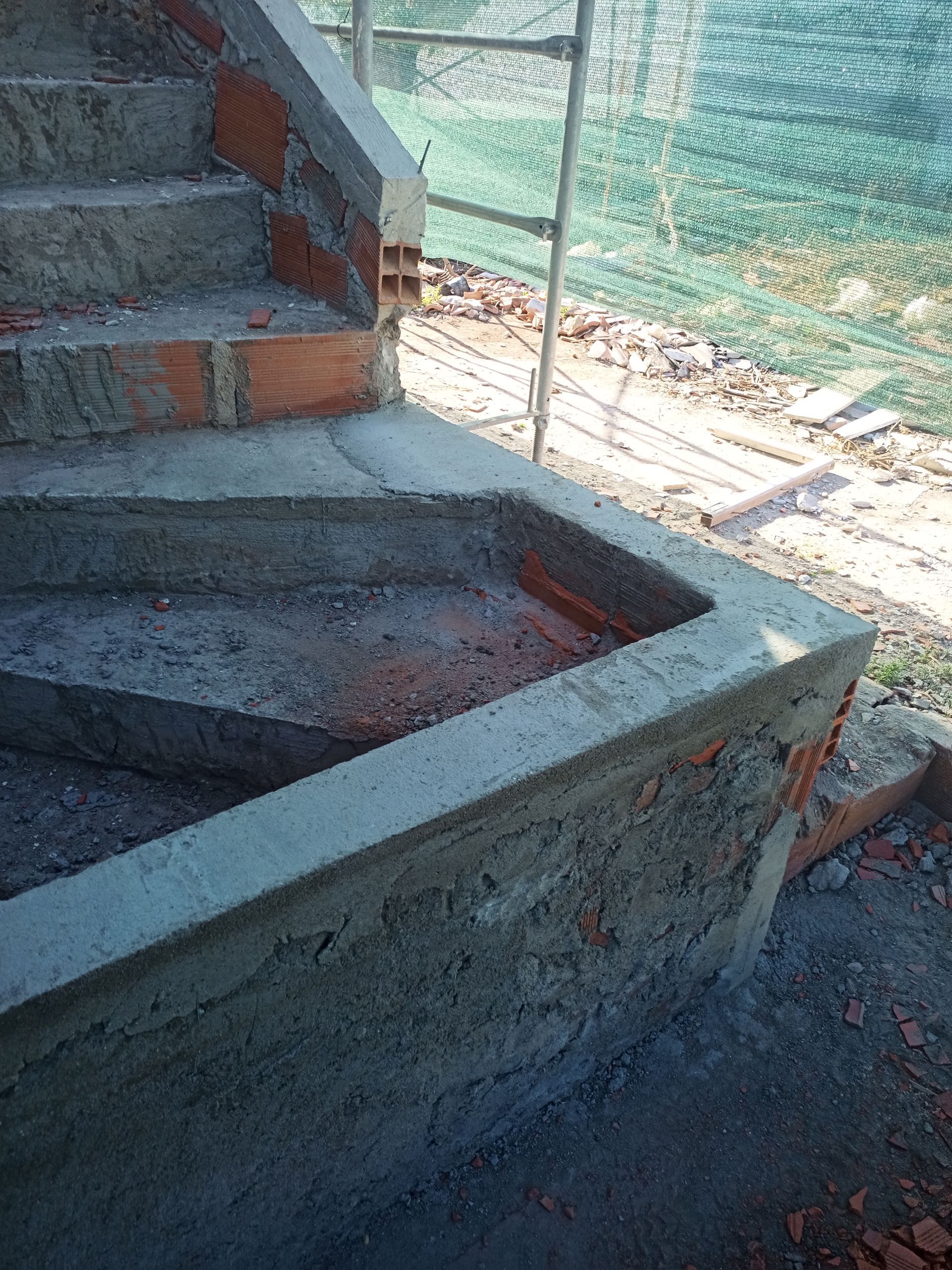 Escadas de concreto e tijolo em construção, ao ar livre.