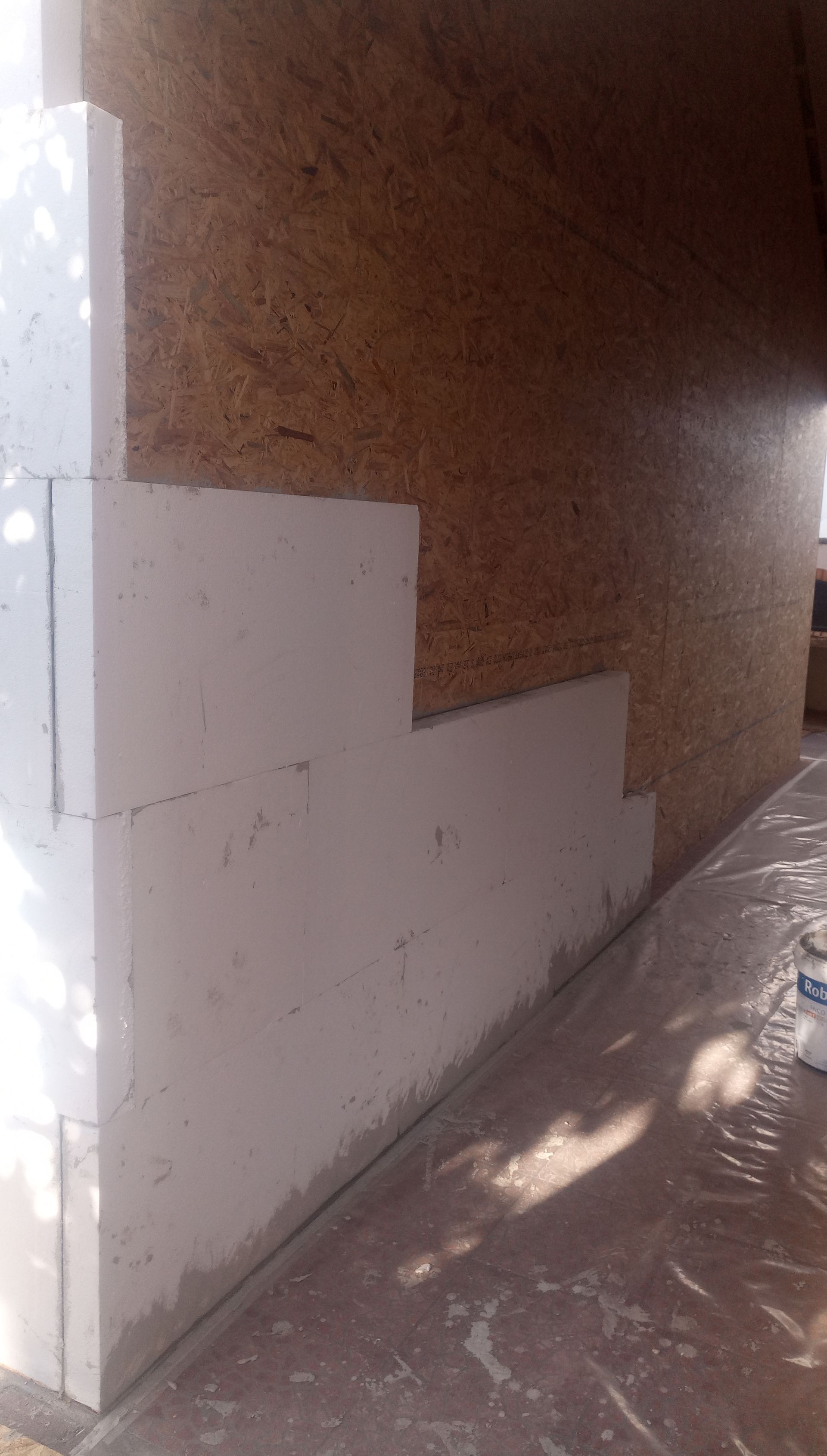 Construção: Parede de blocos brancos parcialmente revestida com gesso, painéis de madeira marrom.