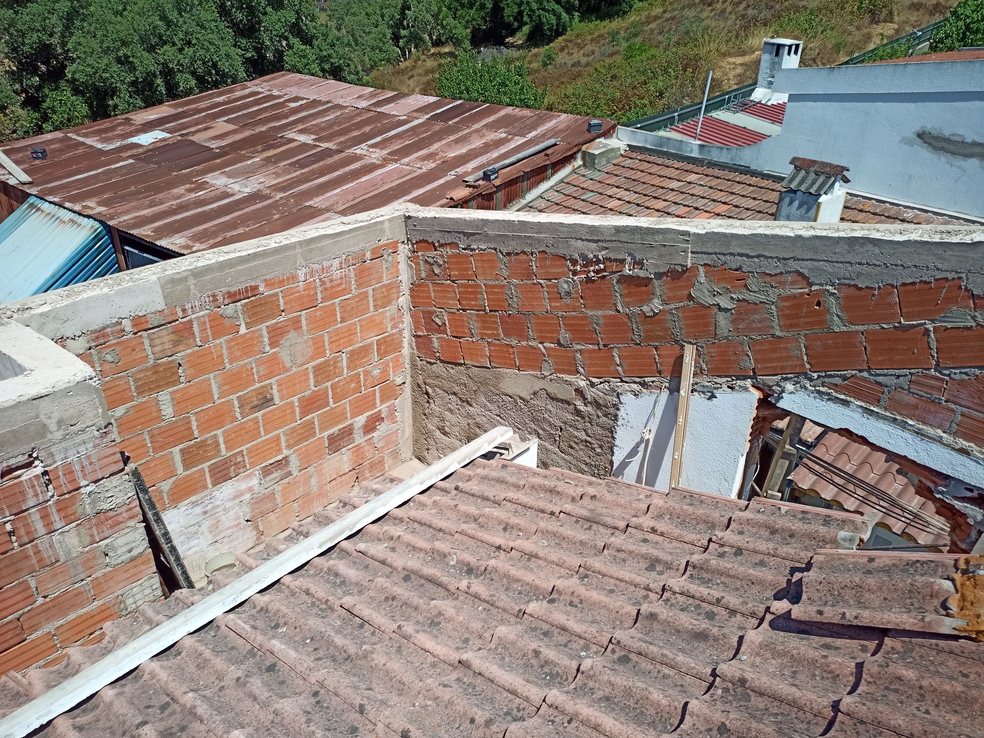 Vista aérea de edifícios com paredes de tijolo vermelho e telhados de telha, em um dia ensolarado.