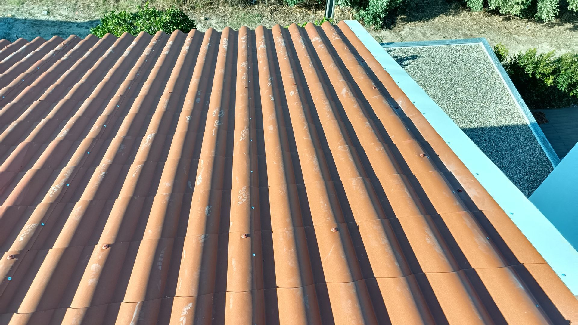 Telhas onduladas marrons com parte da borda do edifício visível.