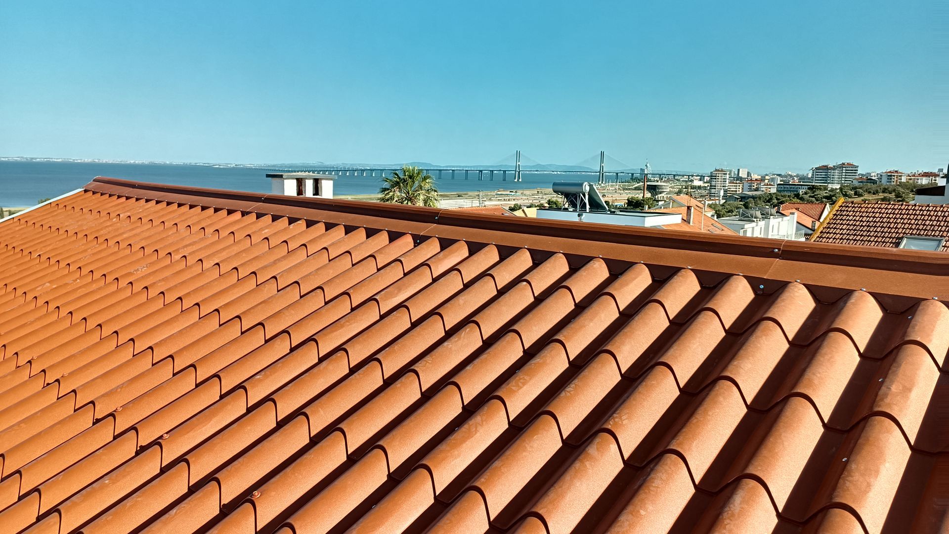 Telhado de telhas de terracota com vista para a cidade costeira em um dia claro.