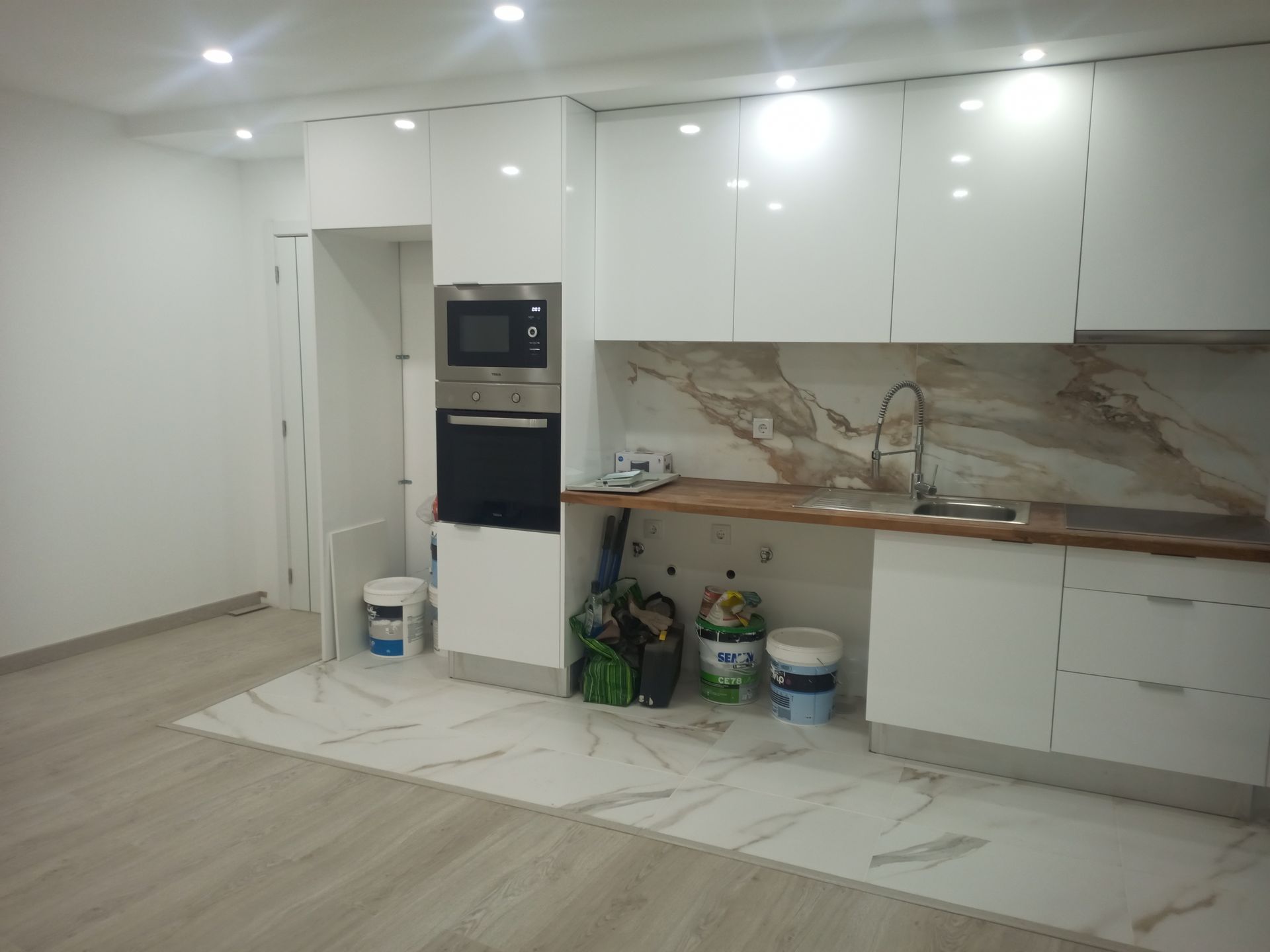 Cozinha branca com backsplash de mármore, armários e eletrodomésticos. Interior de construção nova.