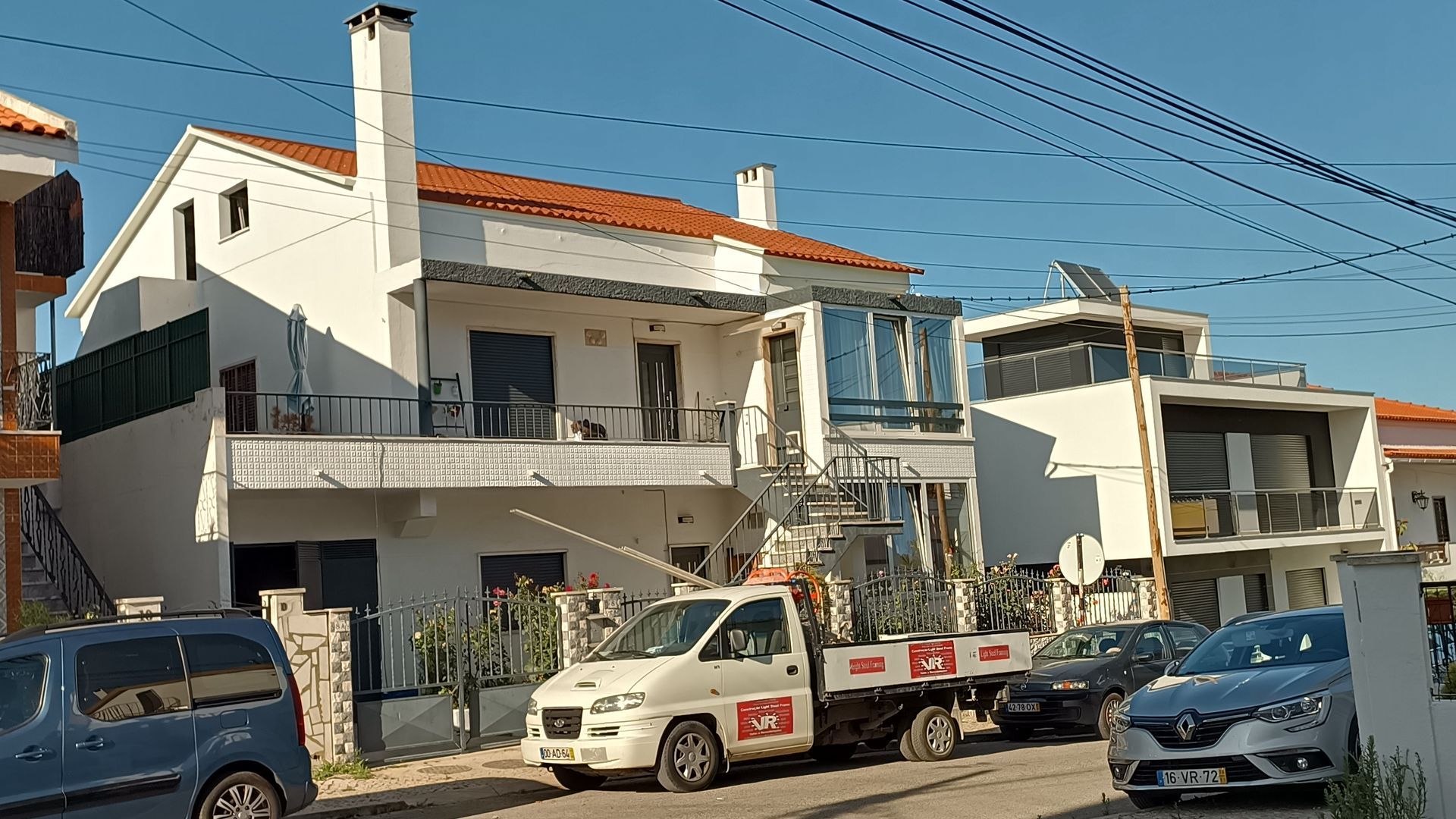 Casa branca com um guincho estacionado em frente, vista da rua.