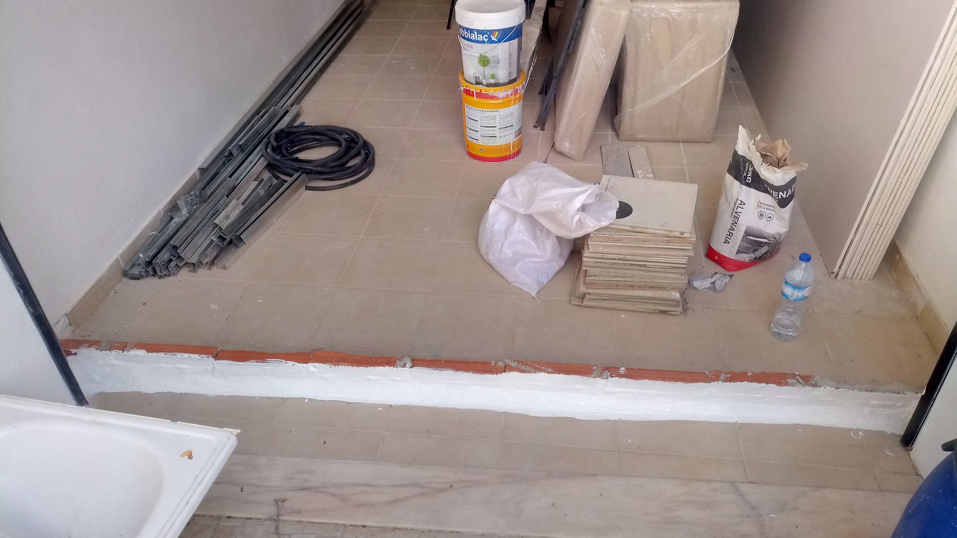 Corredor em construção, com materiais de construção e entulho no chão.