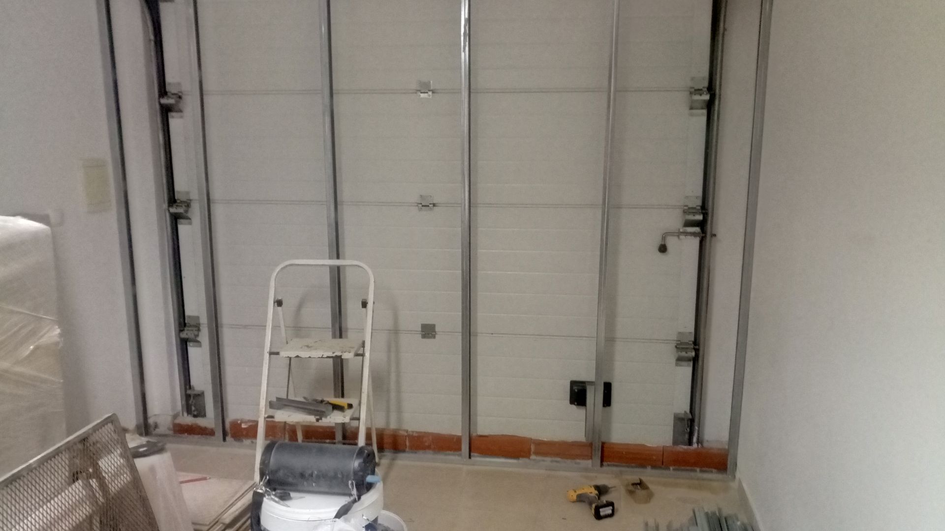 Interior em construção com estrutura metálica, escada e ferramentas.