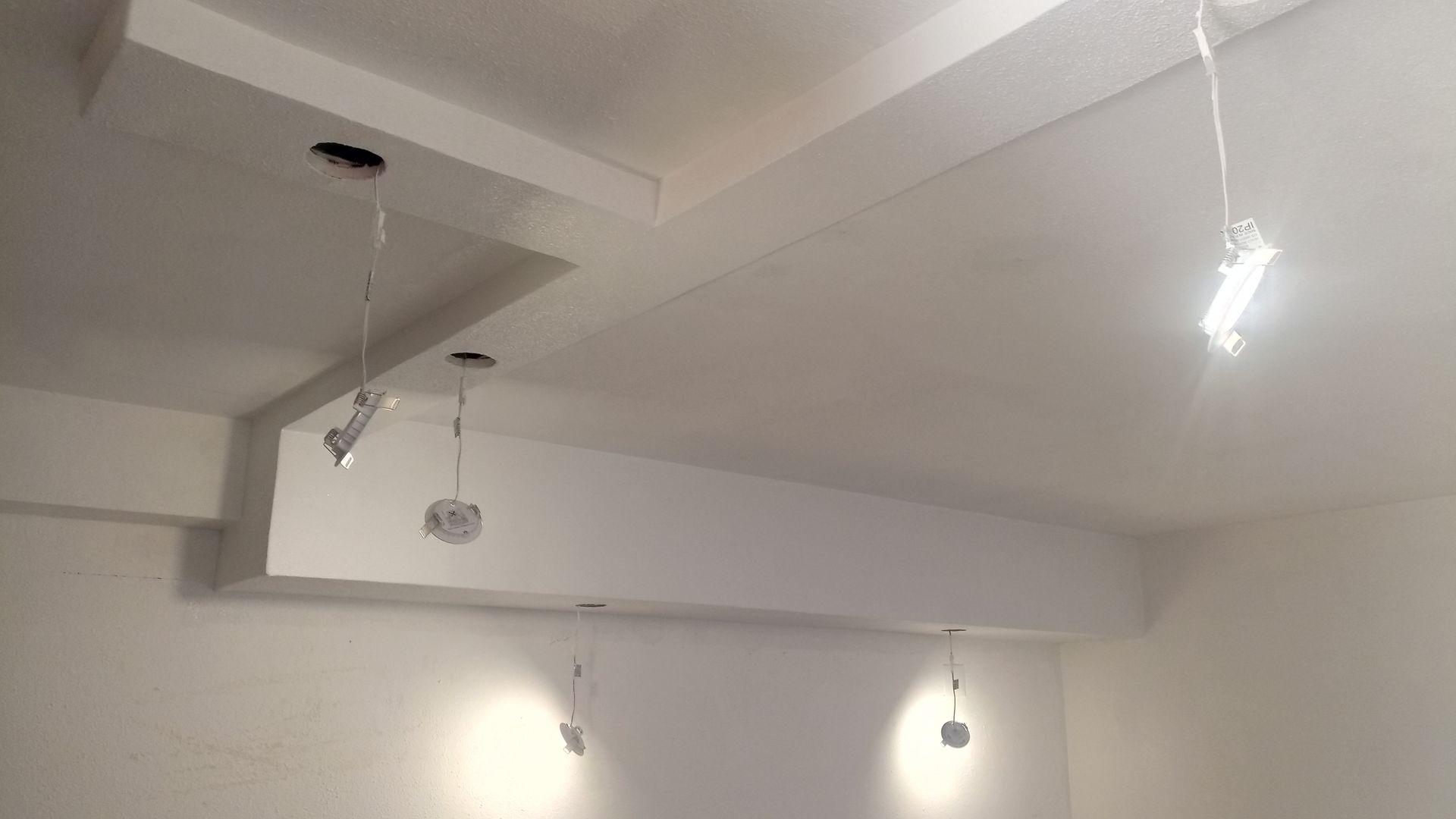 Quarto com teto branco, vigas embutidas e luminárias pendentes.