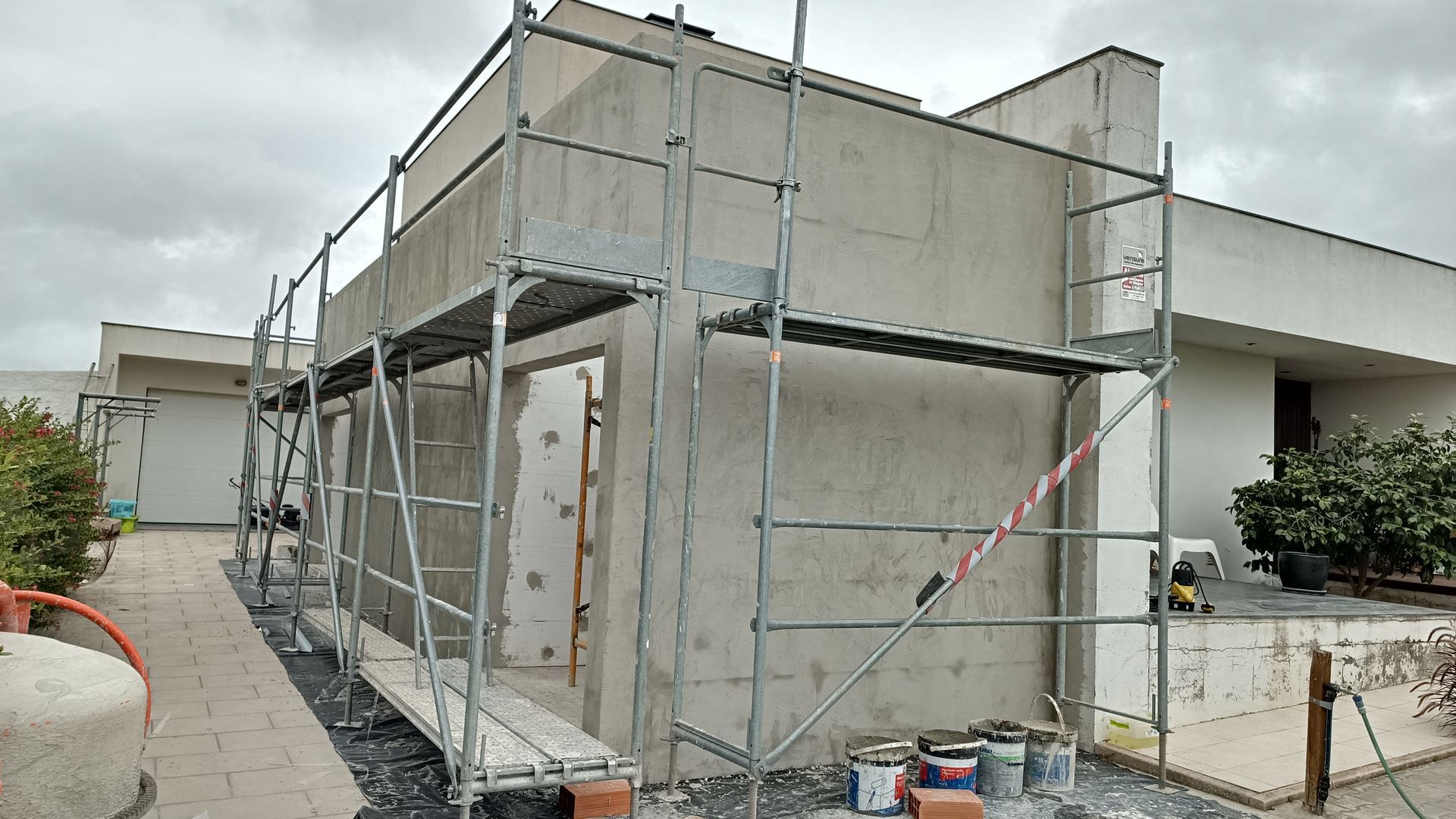 Andaimes em um prédio em construção. As paredes externas são visíveis e baldes de tinta estão embaixo.
