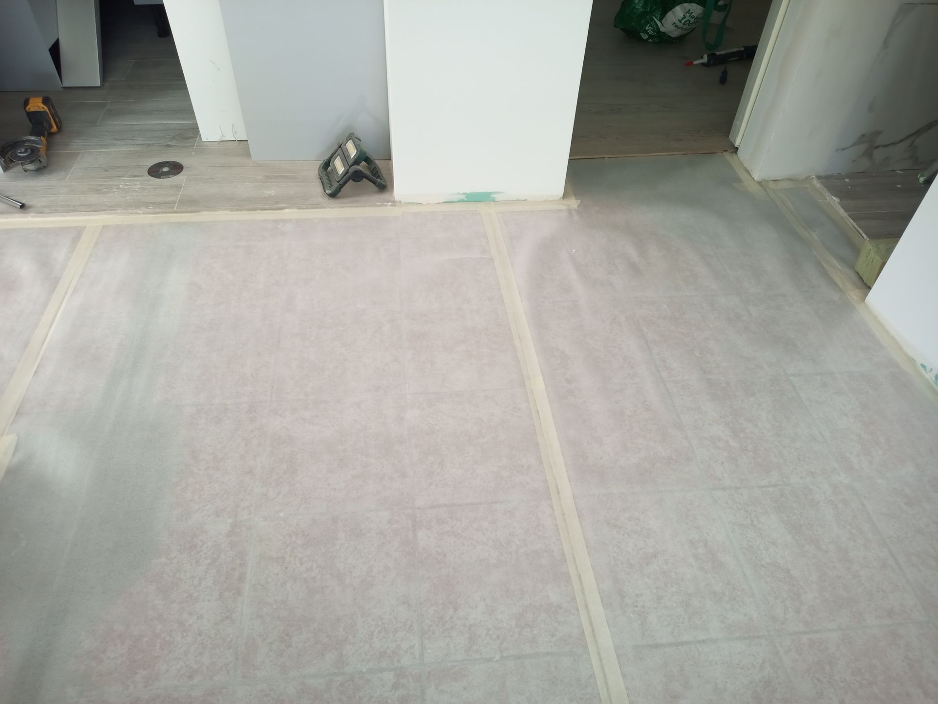 Projeto de revestimento de piso: papel protetor fixado com fita adesiva, cobrindo o piso com portas visíveis ao fundo.
