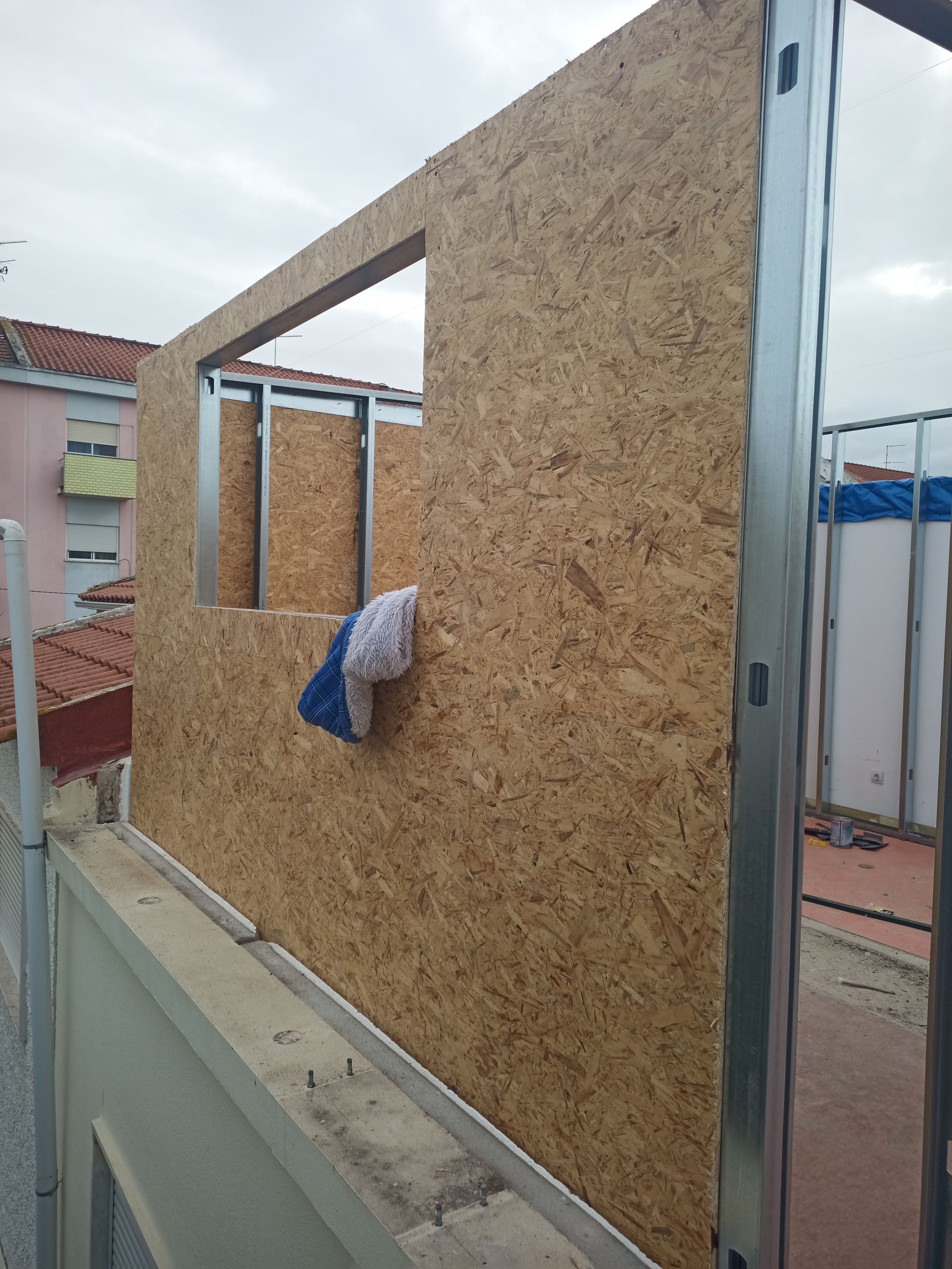 Parede externa em construção com estrutura de OSB e metal. Abertura da janela visível.
