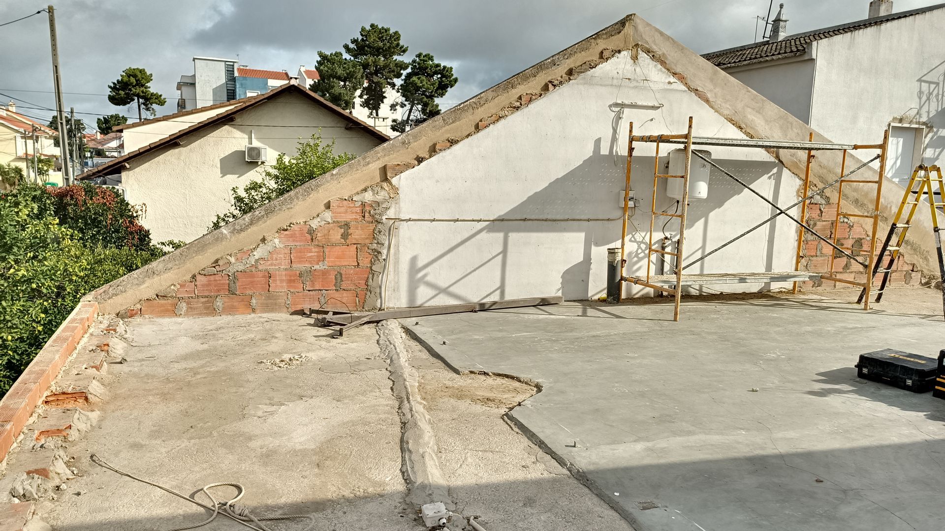 Canteiro de obras com telhado parcialmente demolido e andaimes.