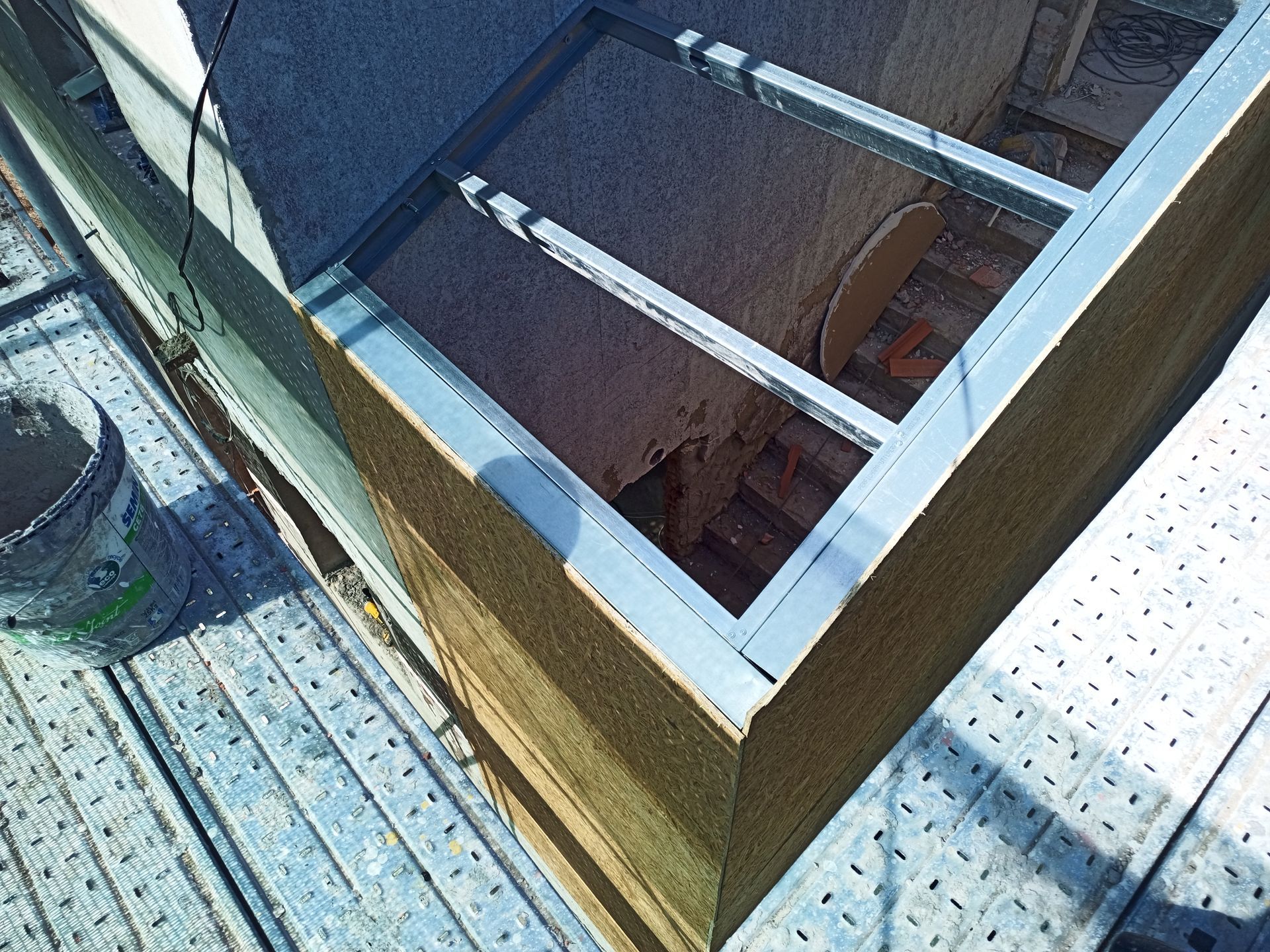 Canto de obra com estrutura metálica, isolamento e andaimes. Uma plataforma elevatória está sobre a estrutura.