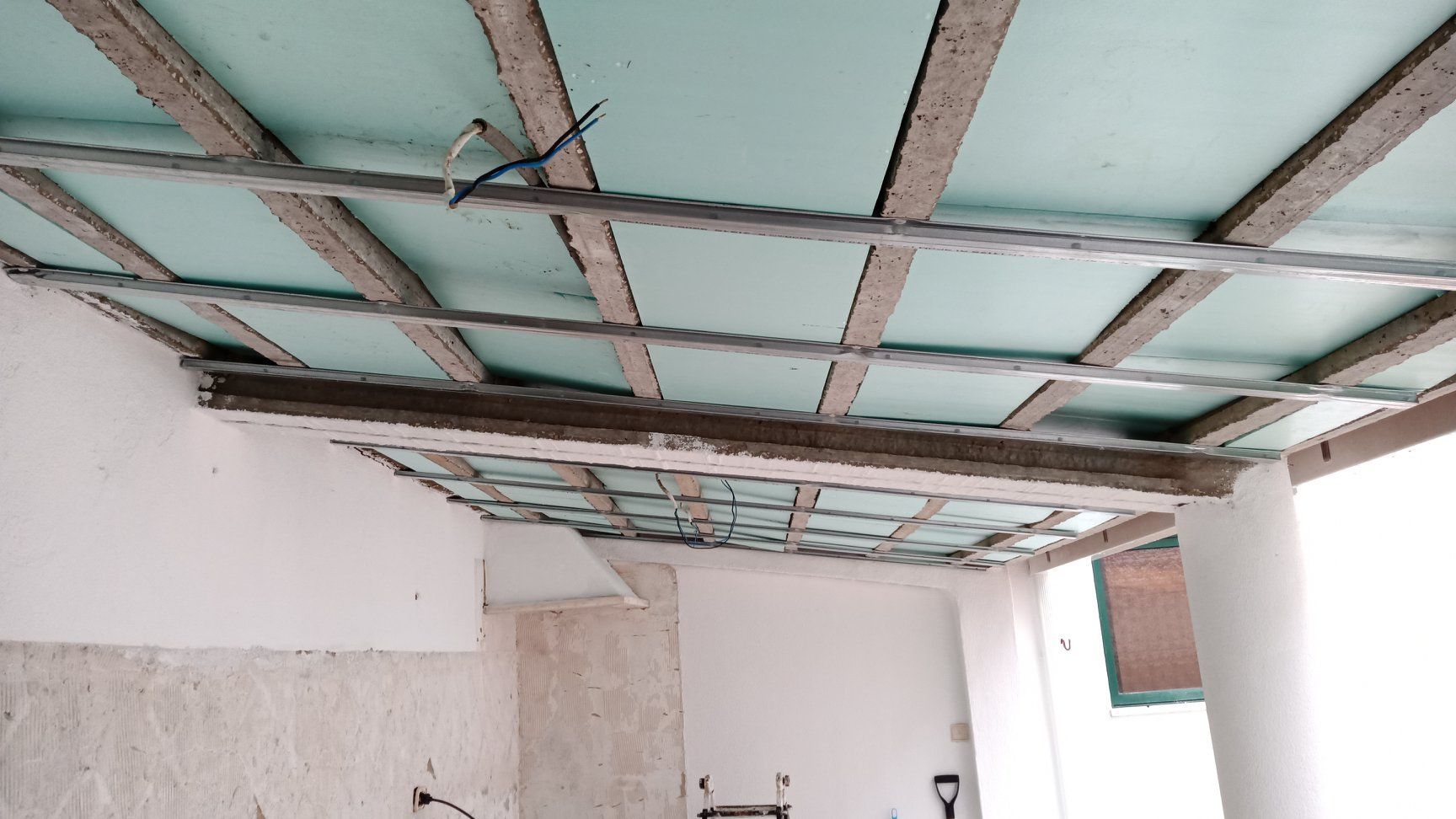 Teto em construção: estrutura metálica que suporta placas de isolamento verde.