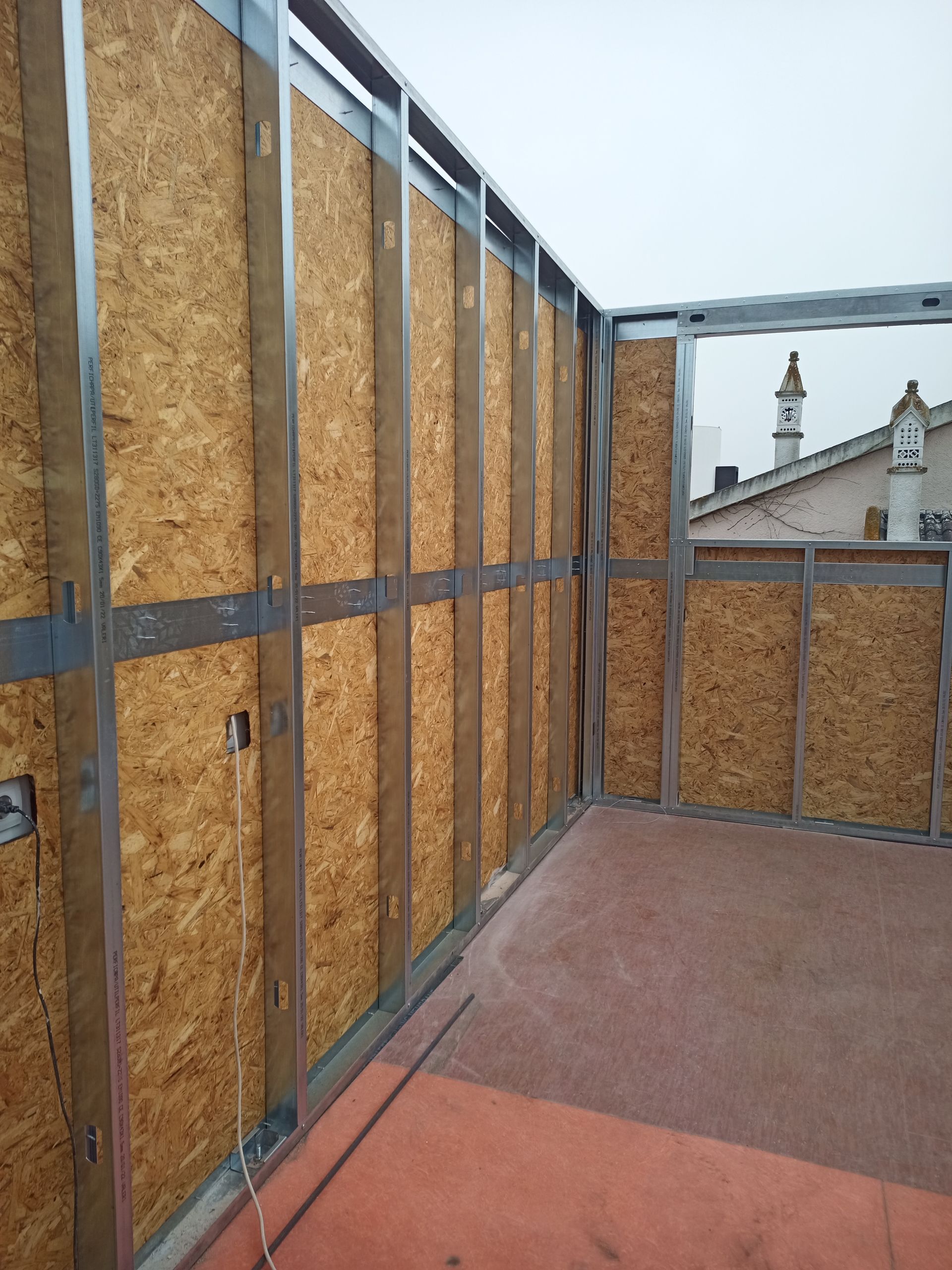 Construção de parede com estrutura metálica e revestimento em placa OSB no telhado.