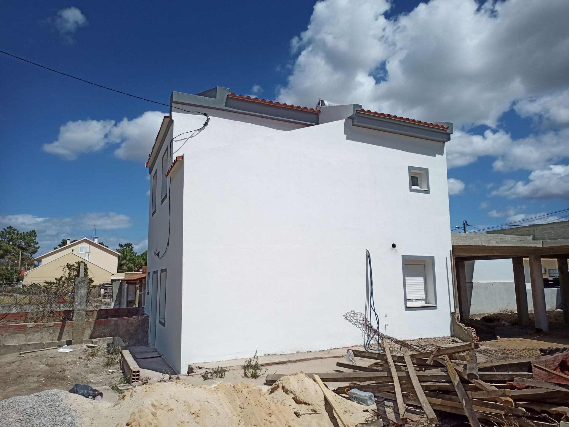 Prédio branco em construção contra um céu azul com nuvens dispersas.