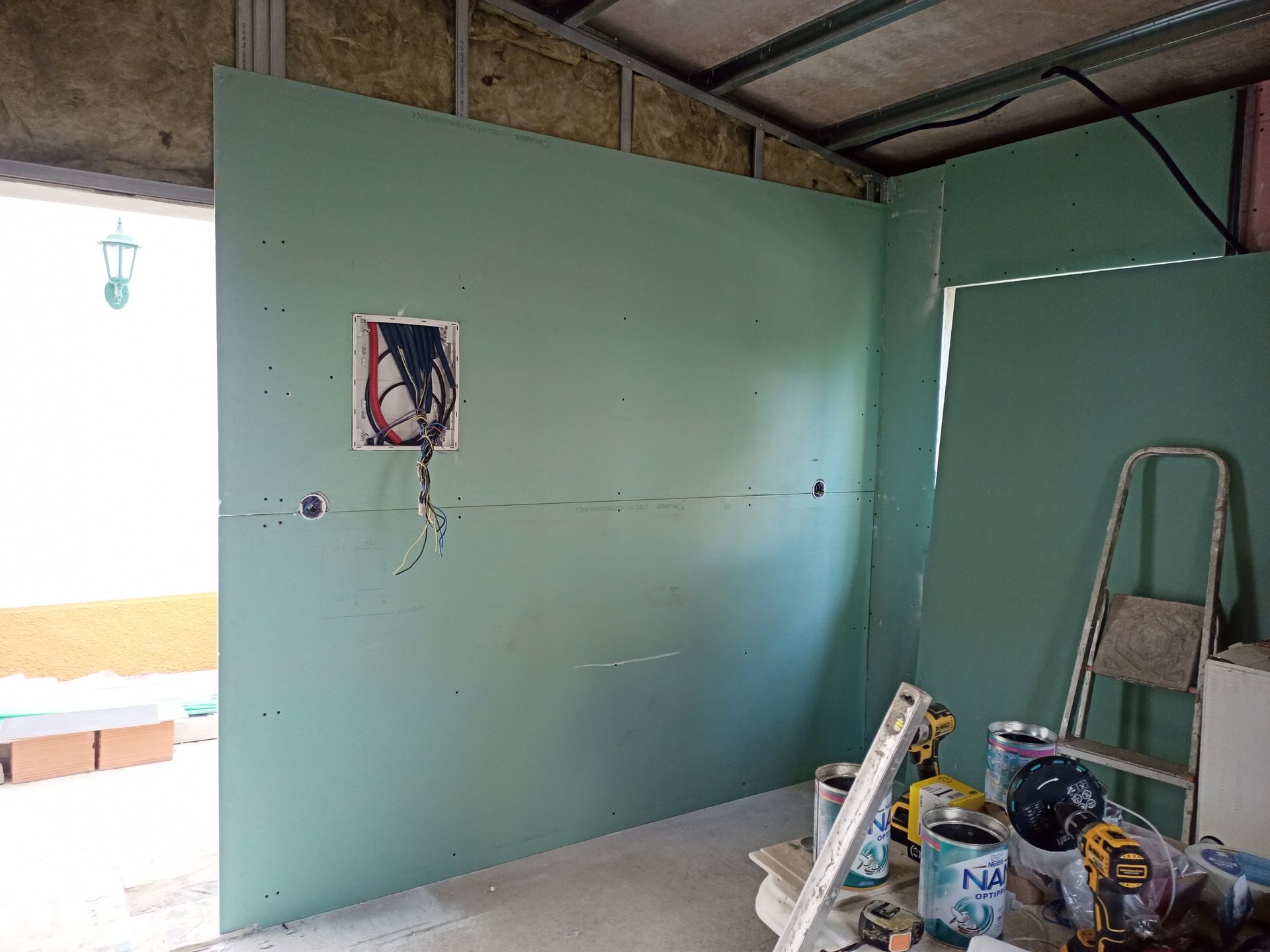 Construção interna: drywall verde parcialmente instalado, caixa elétrica, vigas expostas.