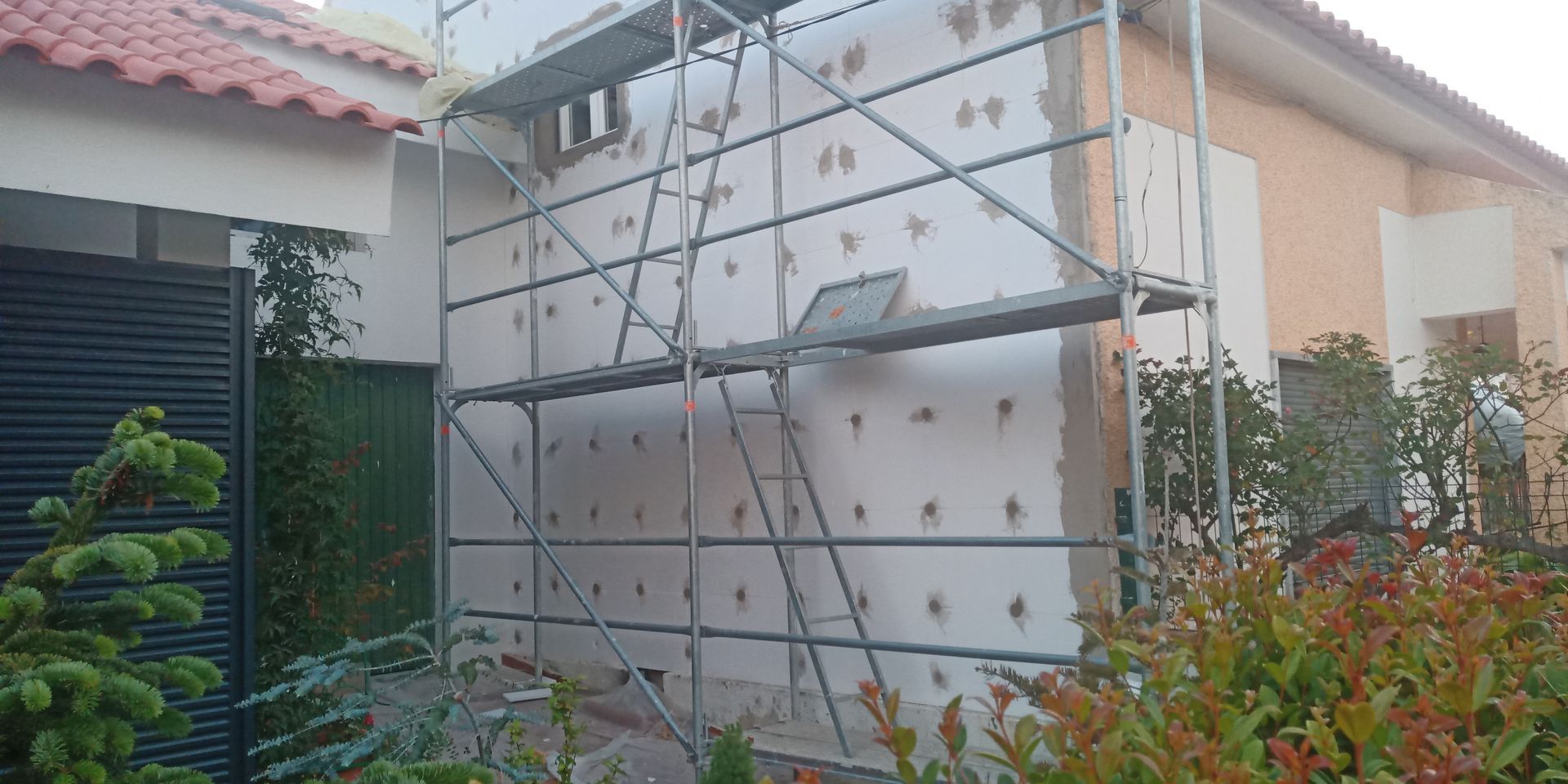 Exterior de um edifício com andaimes e isolamento sendo instalados.