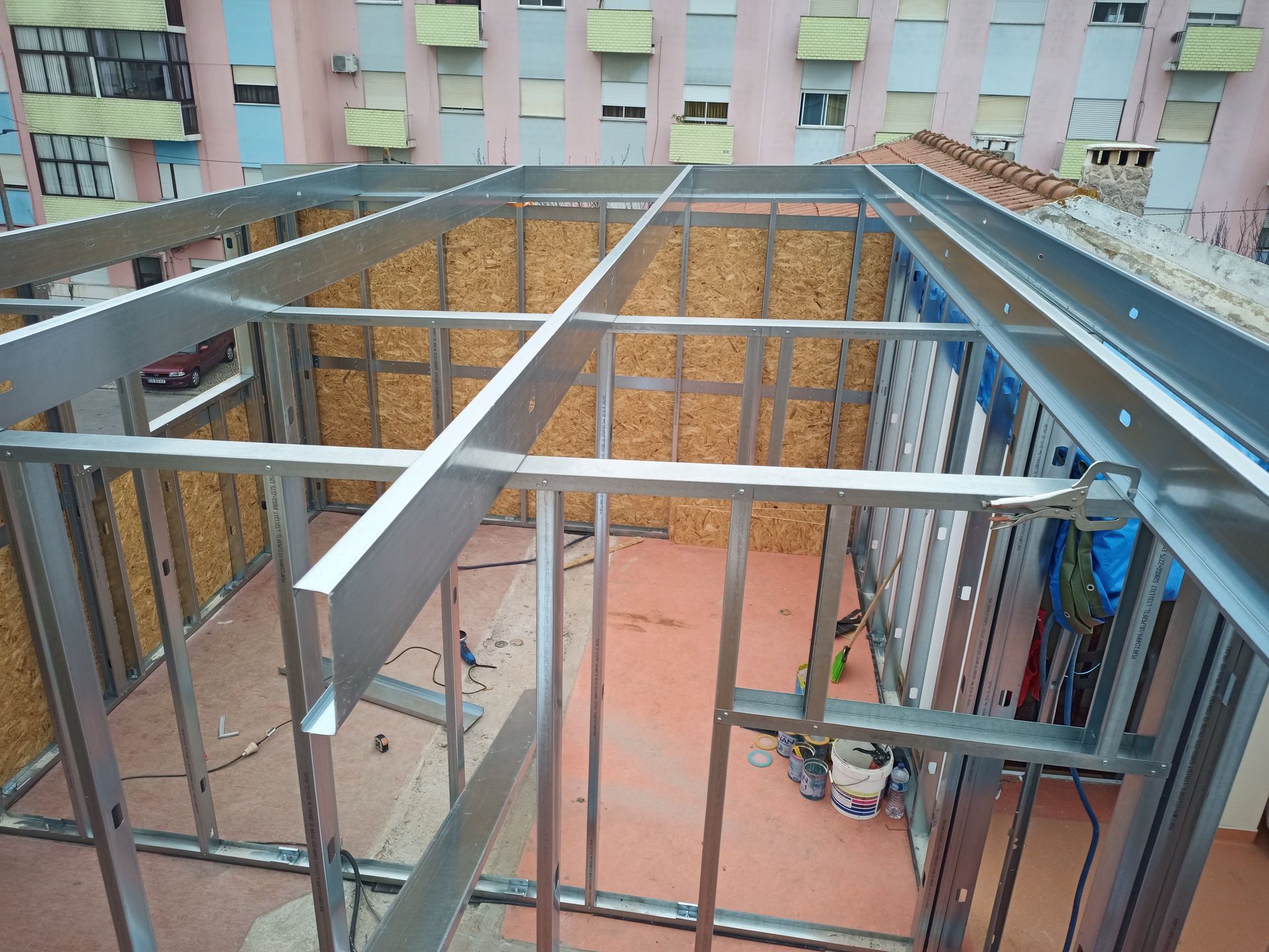 Estrutura metálica de um cômodo em um terraço, com isolamento de madeira aparente.