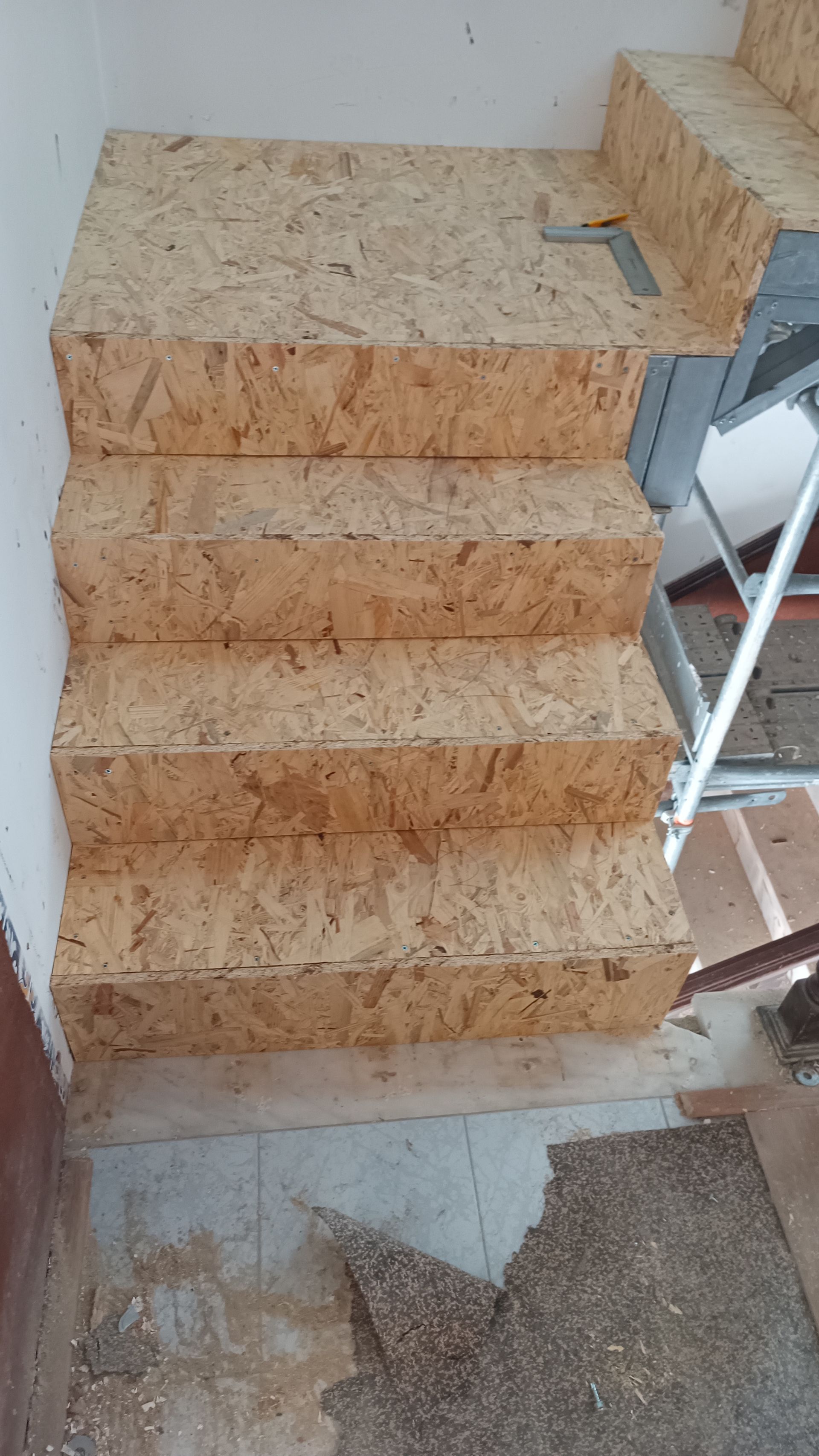 Degraus de OSB contra uma parede branca. Degraus inacabados de uma obra.
