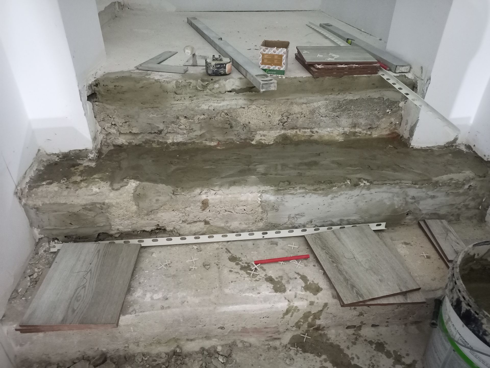 Escada de concreto em construção, com azulejos, ferramentas e materiais.