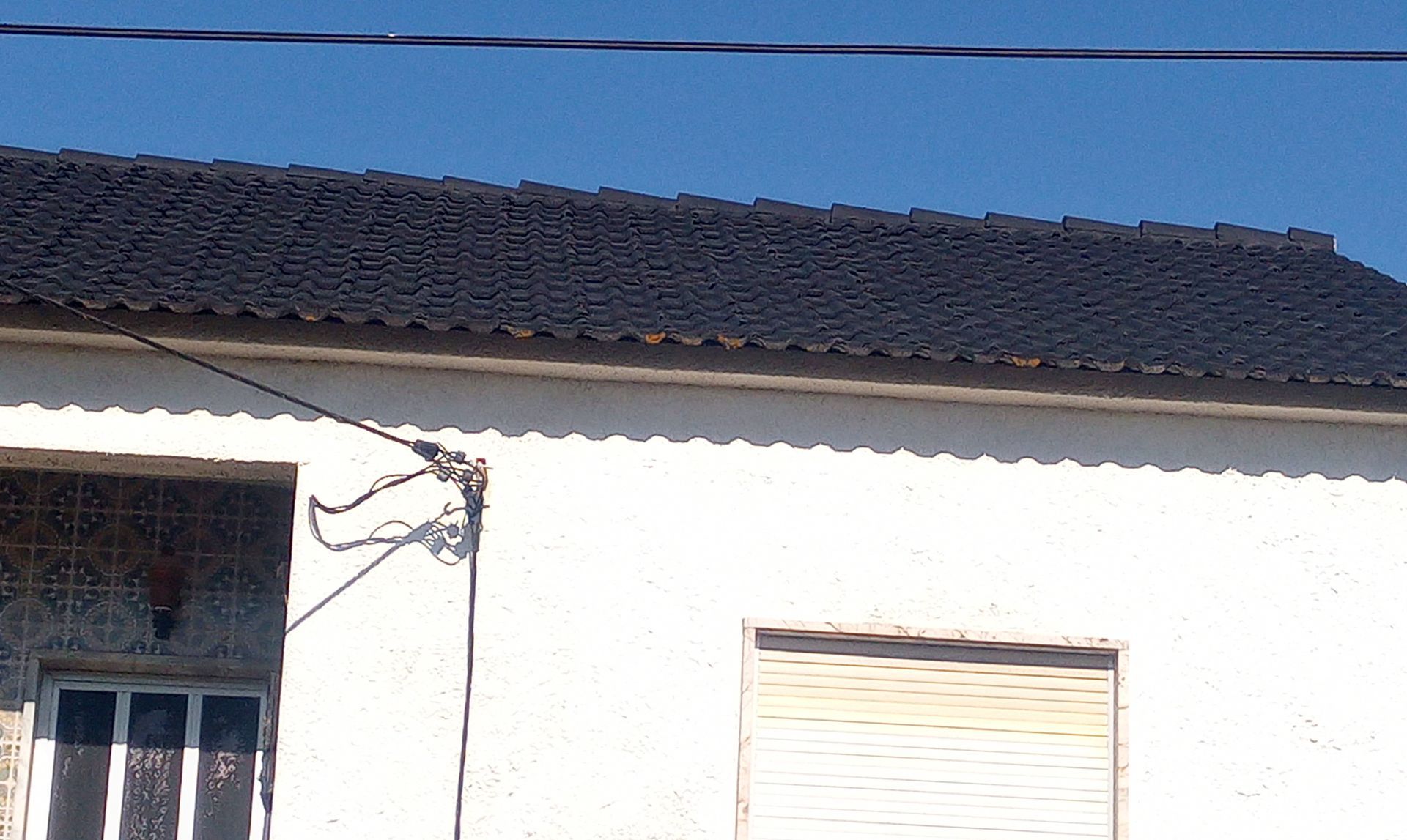 Prédio branco com telhado de telhas pretas contra um céu azul.