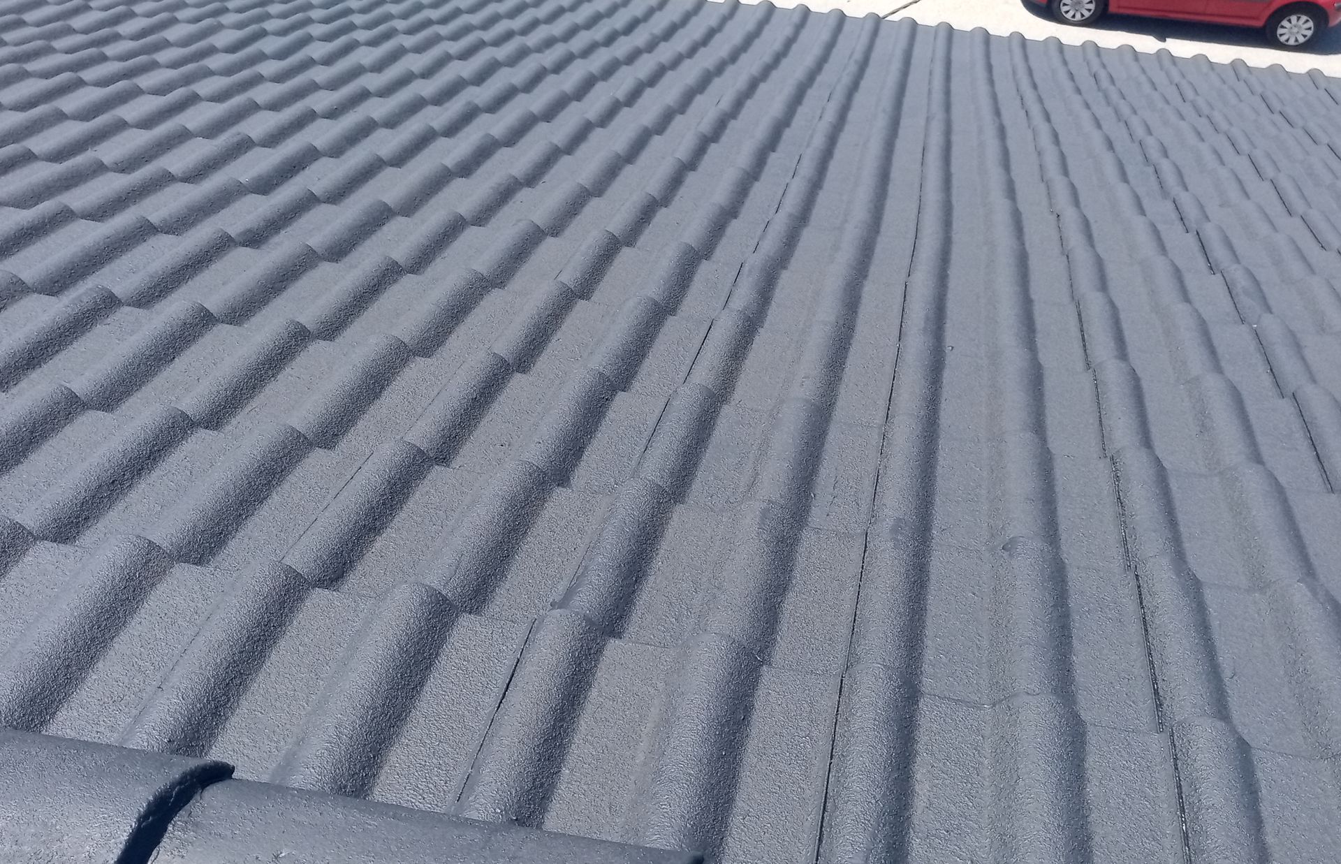 Telhas cinzentas texturizadas. Parte de um carro vermelho é visível no canto superior direito.