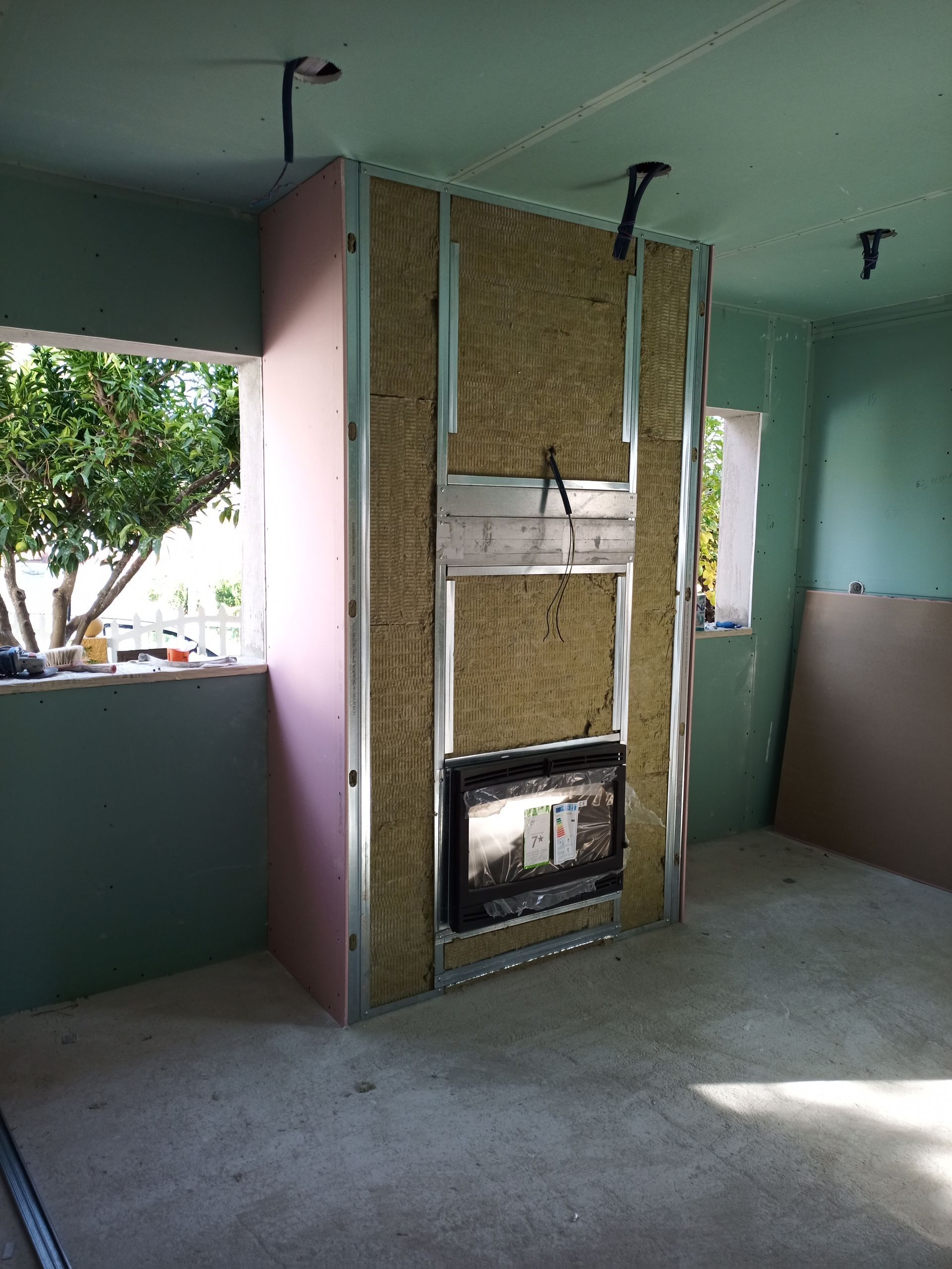 Construção de lareira em um cômodo; estrutura metálica, isolamento e drywall parcialmente instalado.