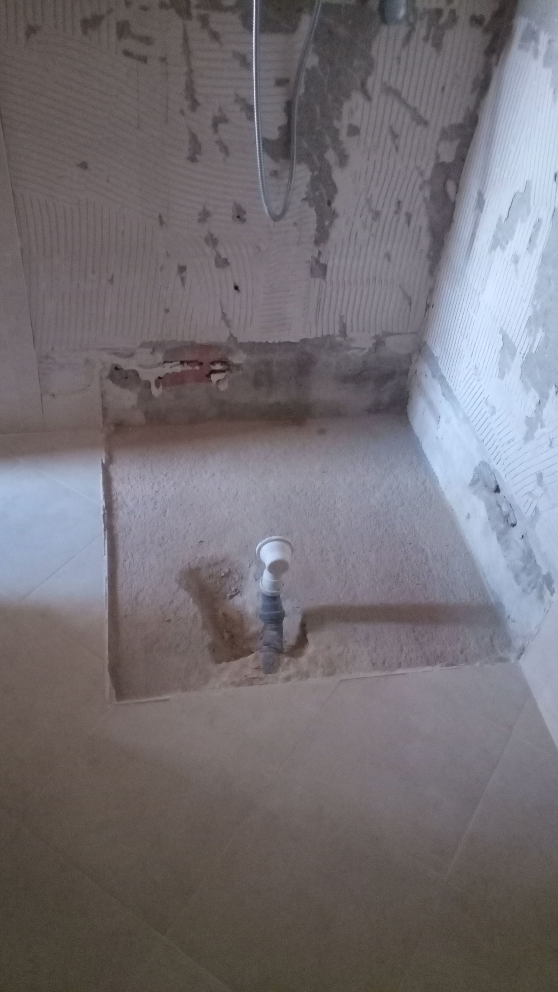 Canteiro de obras, área de chuveiros. Cimento e canos visíveis.