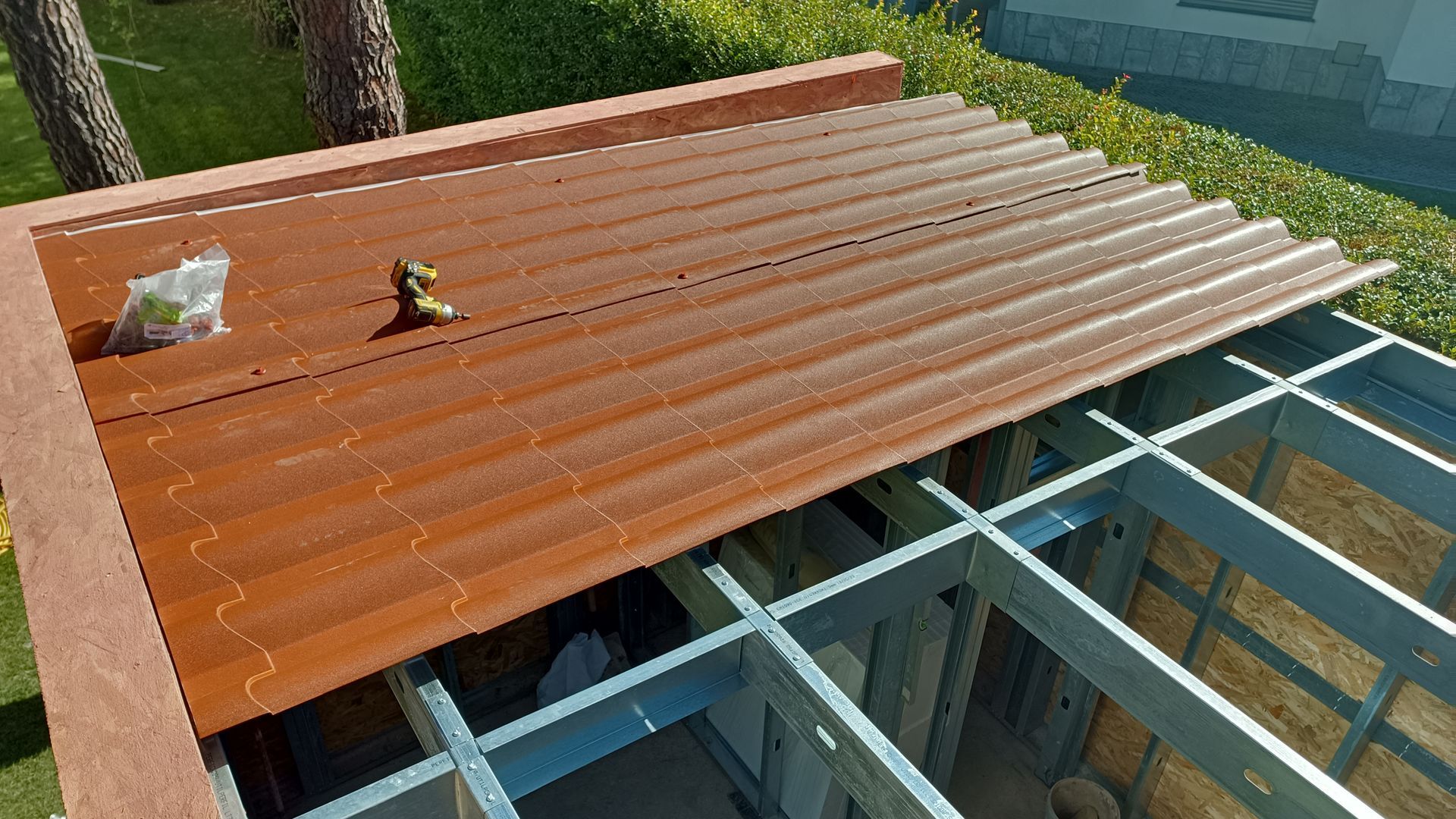 Construção de um telhado de metal ondulado; painéis marrons em uma estrutura metálica, ambiente externo.