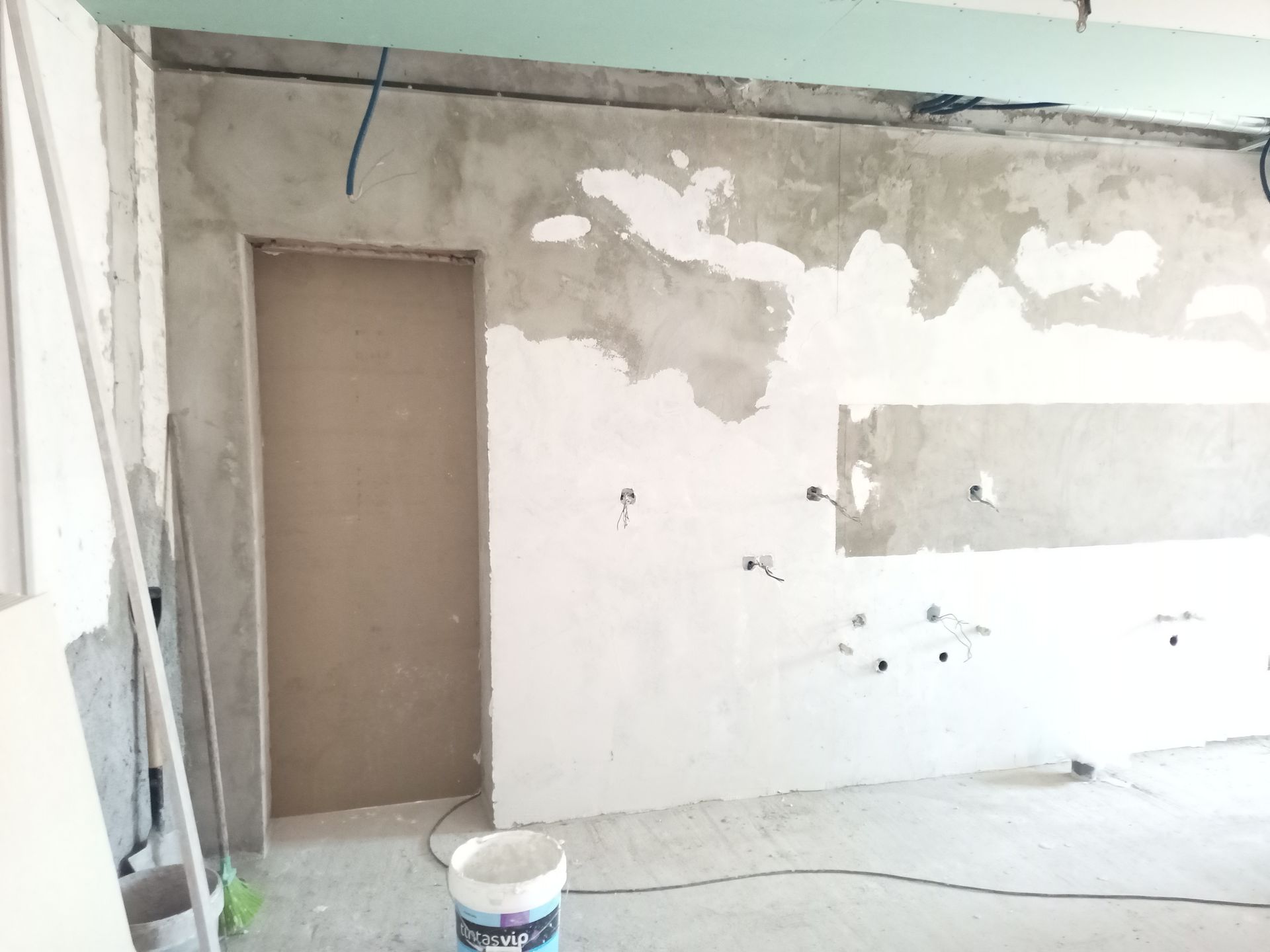 Parede interna em construção com drywall inacabado e batente de porta.