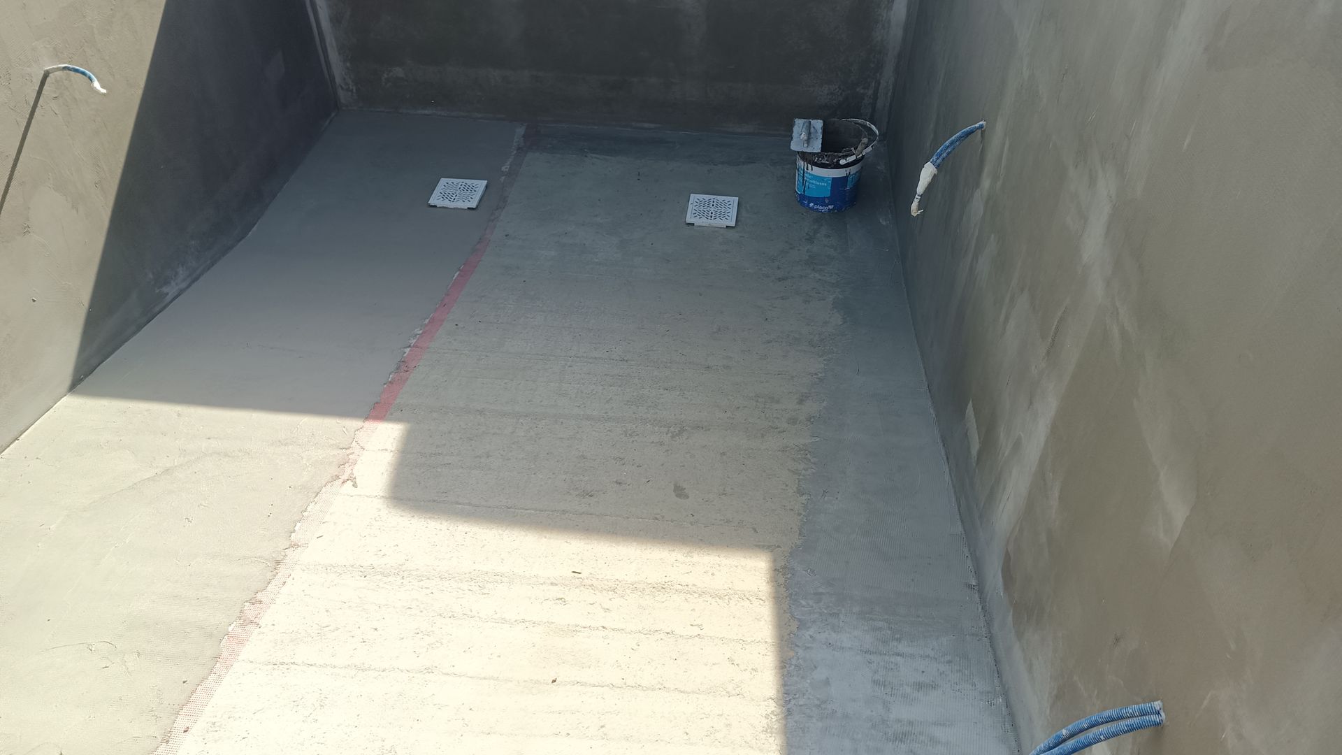 Piscina de concreto em construção, com ralos e instalações hidráulicas.