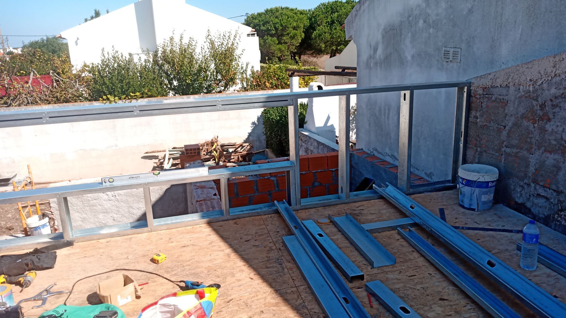 Canteiro de obras com estrutura metálica, alvenaria e materiais de construção.