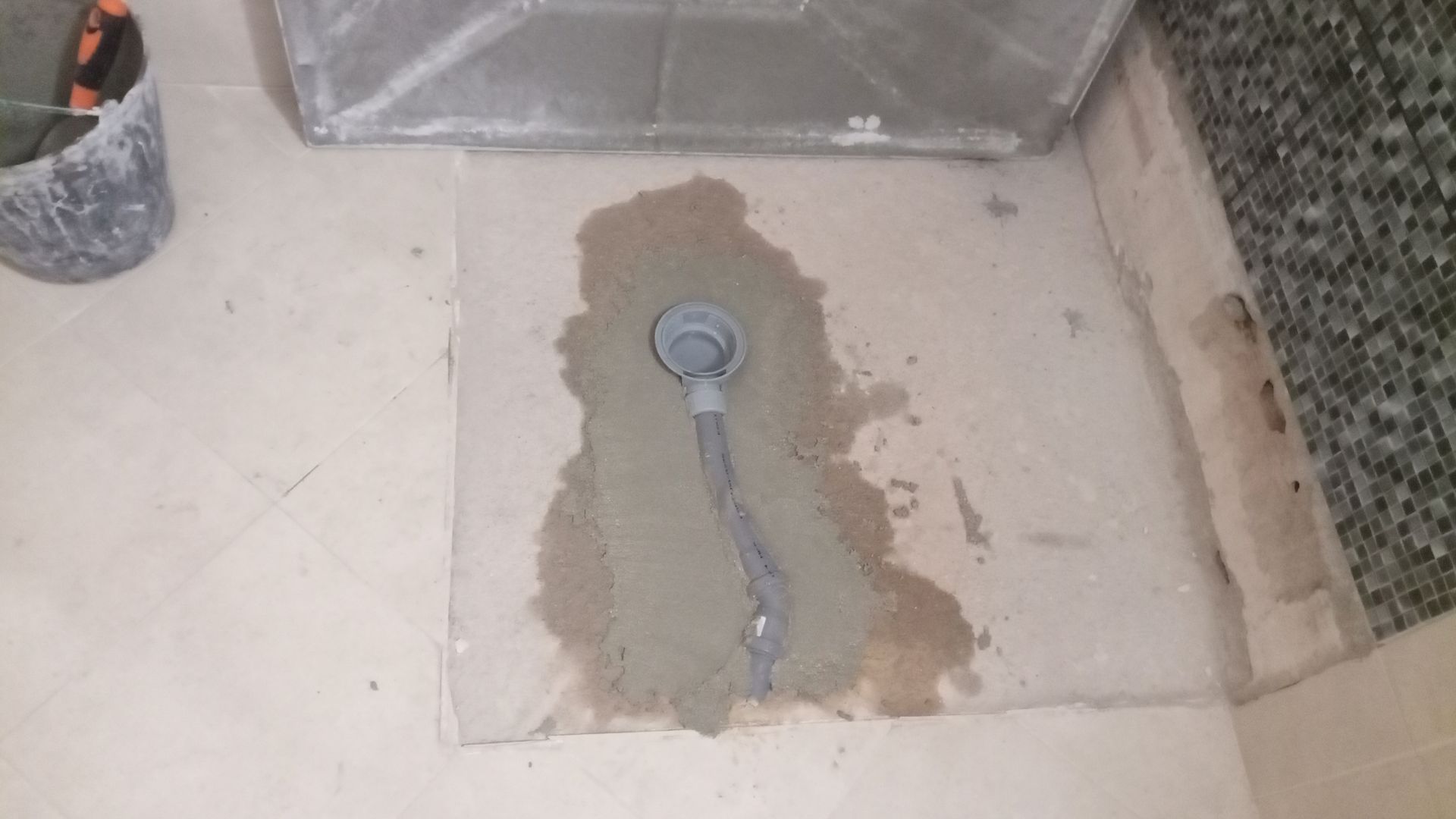 Ralo de concreto no piso com tubo acoplado, envolto em cimento fresco.