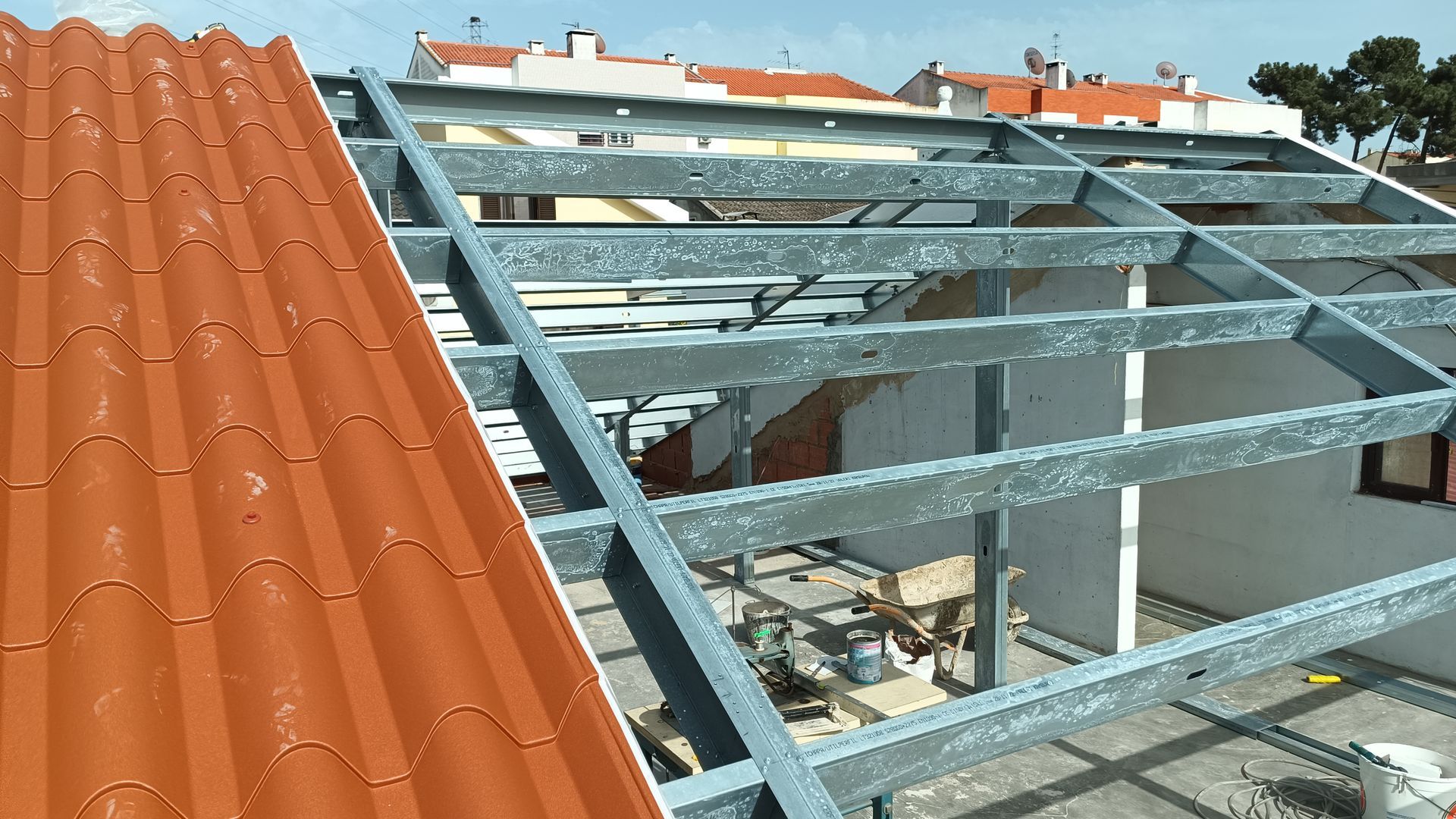 Telhado em construção com estrutura metálica e telhas vermelhas.