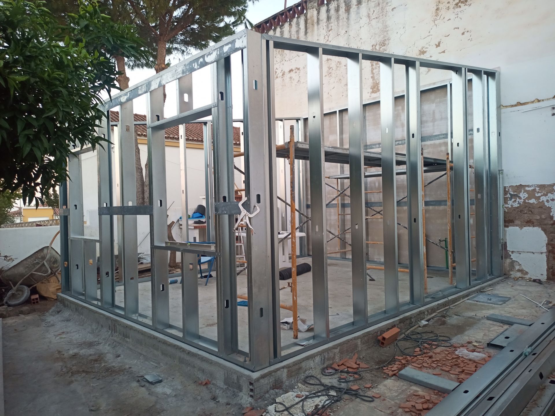 Estrutura metálica de um edifício em construção, ao ar livre. A estrutura possui aberturas para janelas e portas.
