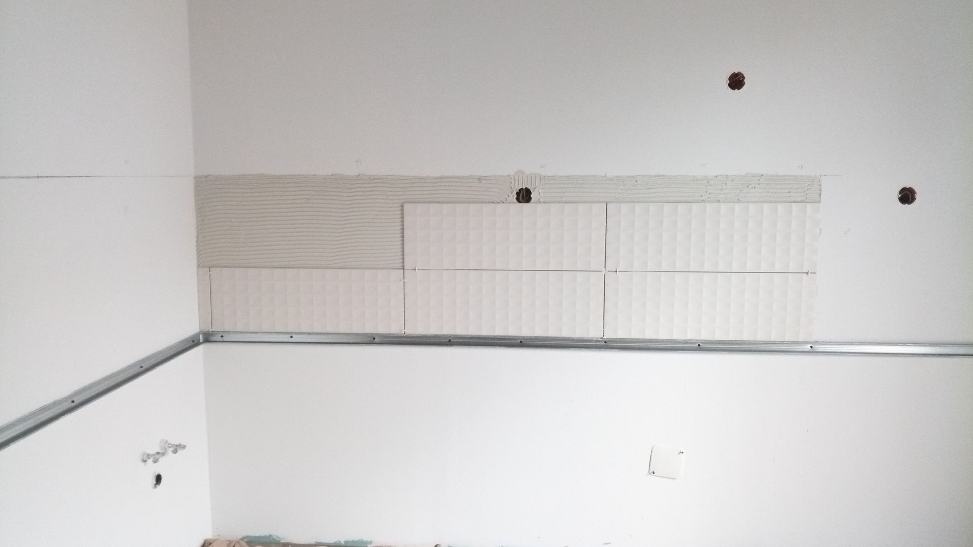 Parede interna com azulejos parcialmente instalados e estrutura metálica.