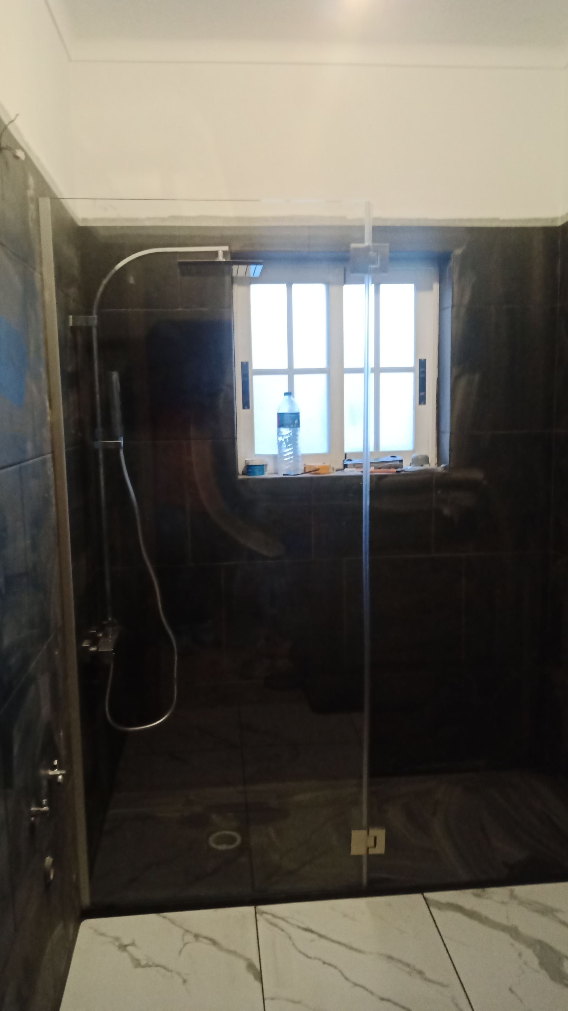 Cabina de duche moderna com azulejos pretos e janela.