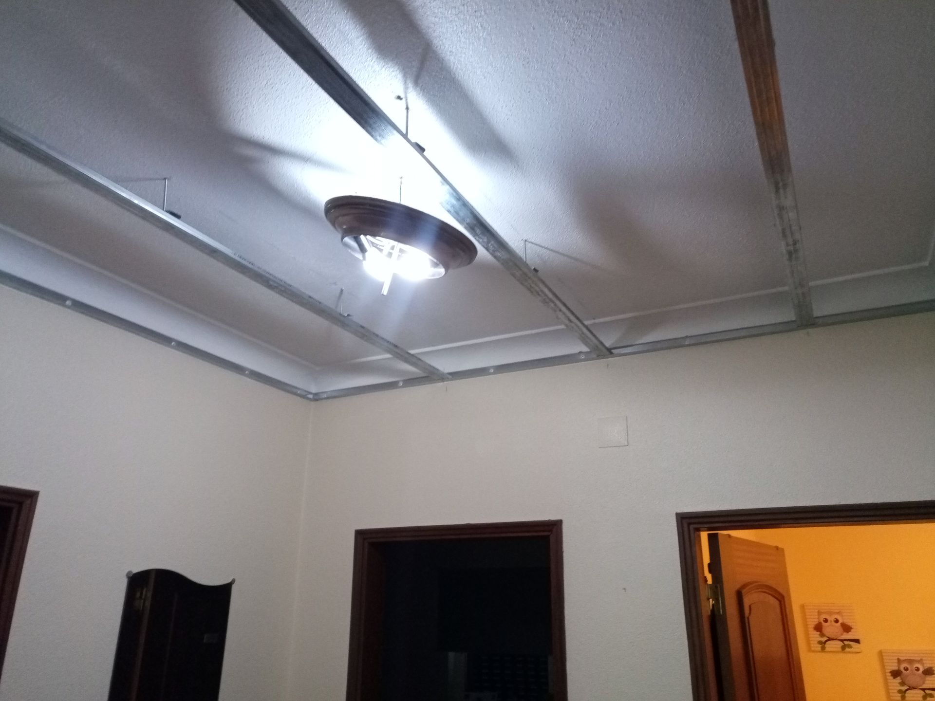 Teto com estrutura metálica aparente e luminária pendente. Foto de interior.