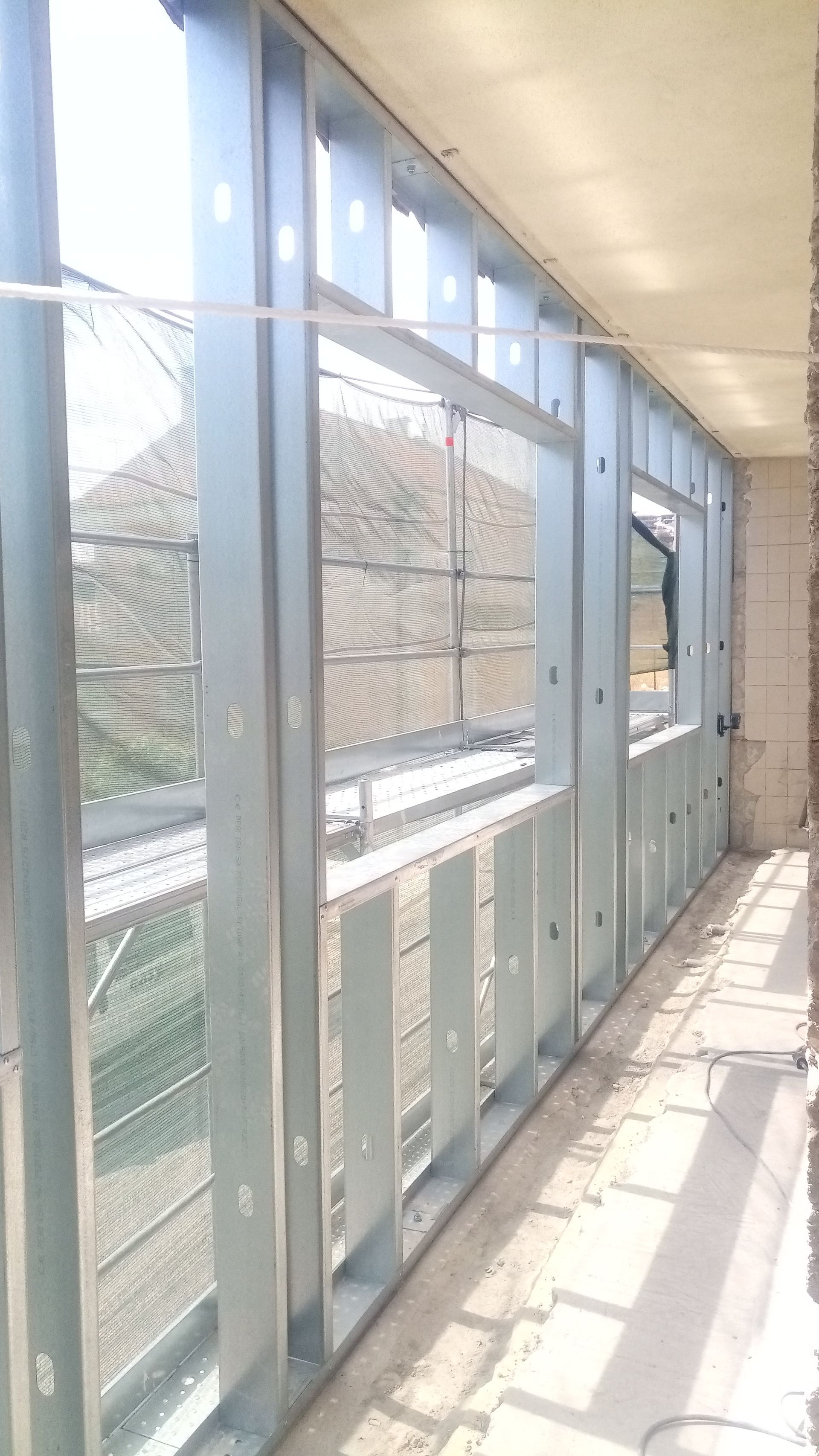 Estrutura metálica de uma varanda com aberturas para janelas; muita luz natural.