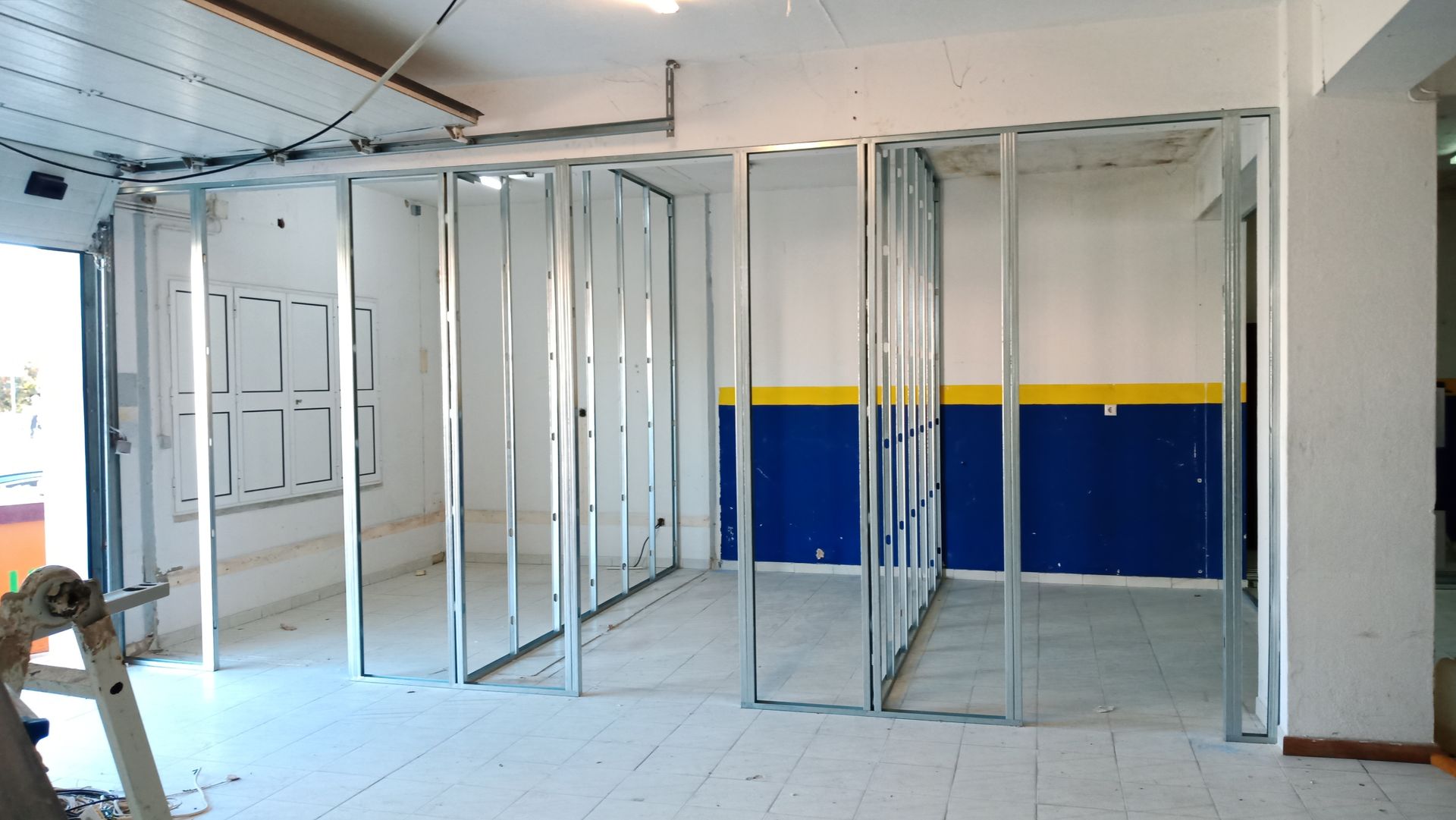 Construção interior: Estrutura metálica para as paredes, sem acabamento. Pintura azul/amarela na parede existente.