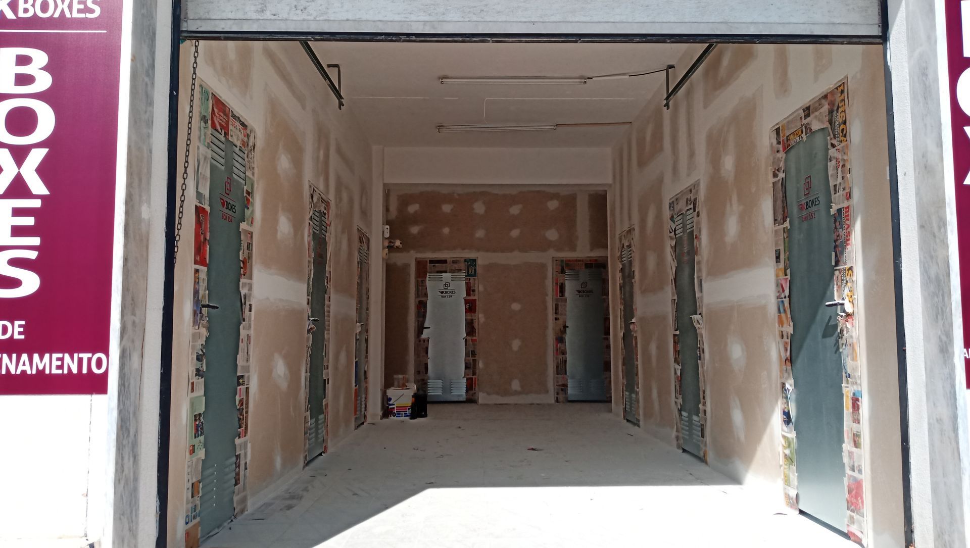 Corredor interno em reforma, com portas e paredes de gesso expostas.