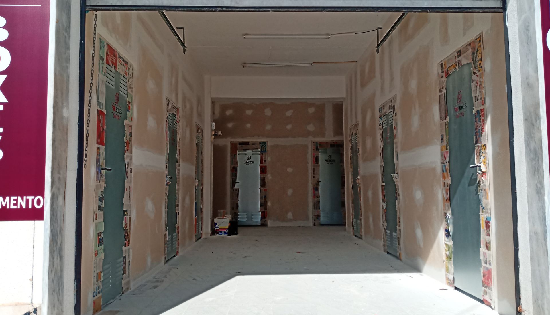 Interior de um edifício em reforma, com portas e paredes de gesso expostas.