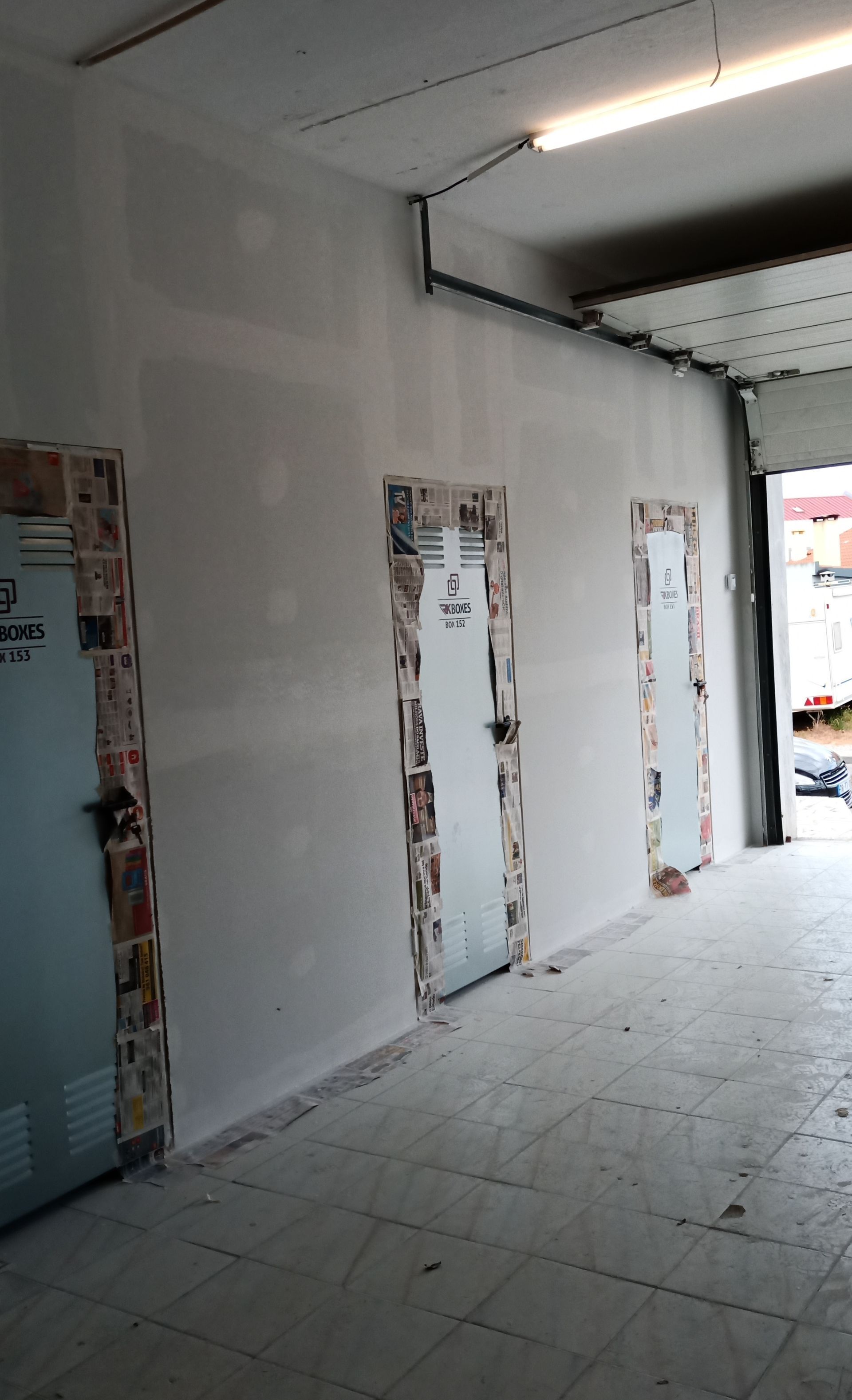 Vista interior de três portas com molduras cobertas de jornal e uma parede recém-rebocada.