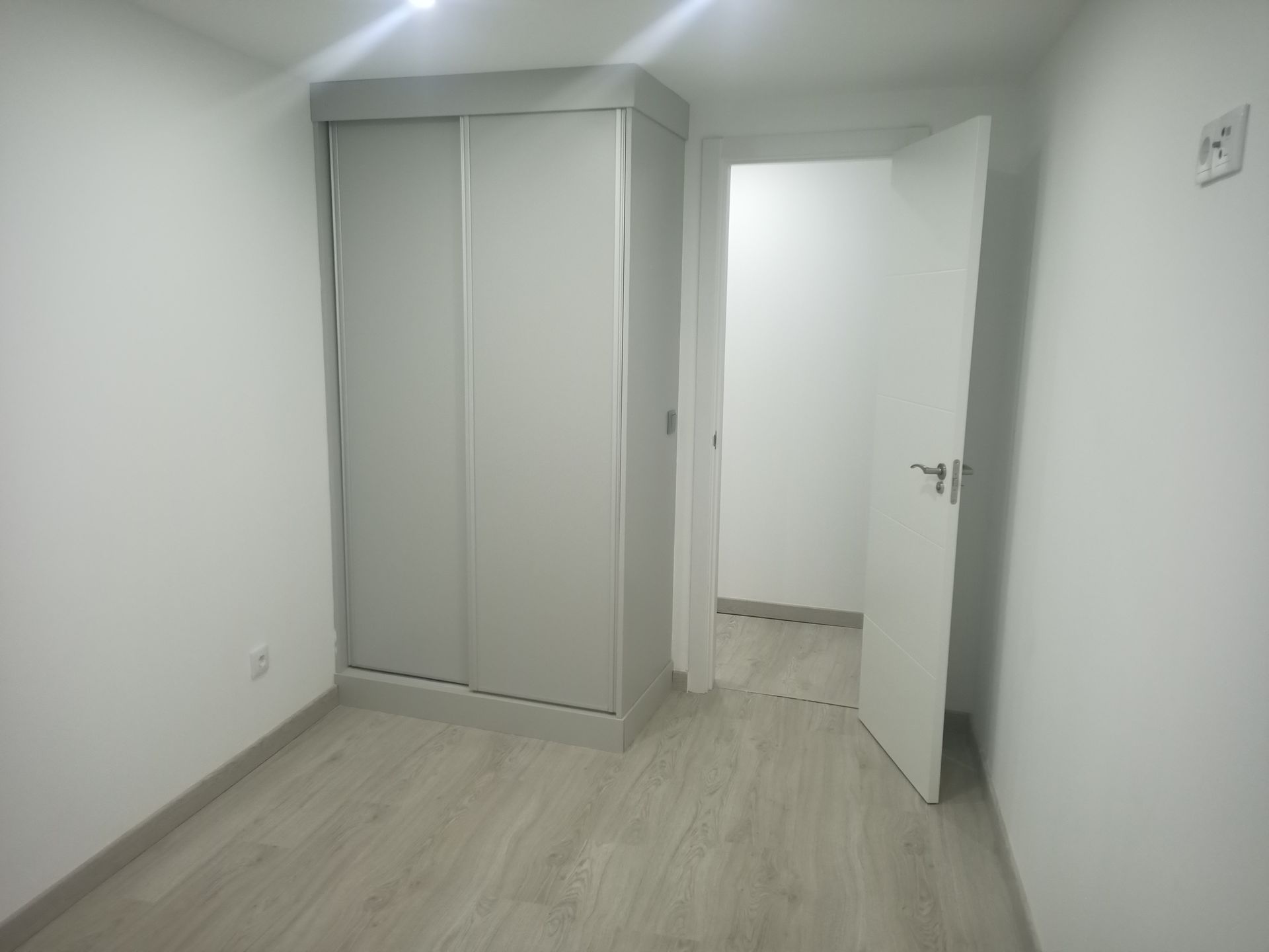 Quarto vazio com um guarda-roupa de portas de correr e uma porta aberta.
