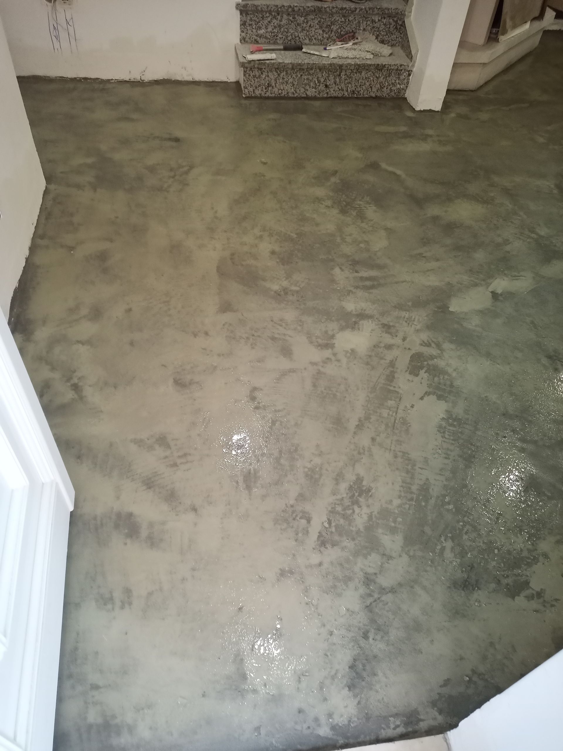 Piso de concreto cinza com escada de mármore ao fundo.