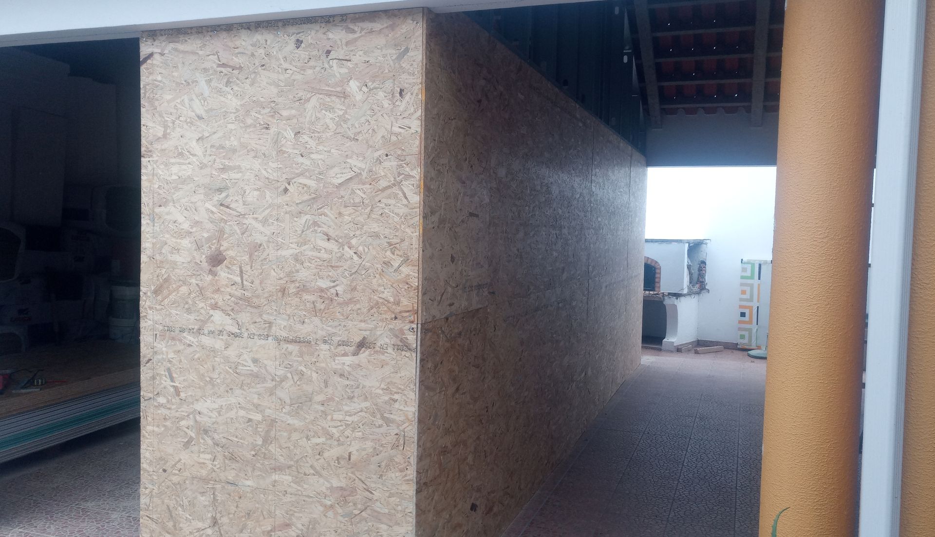 Parede de aglomerado em um edifício com abertura para uma área externa.